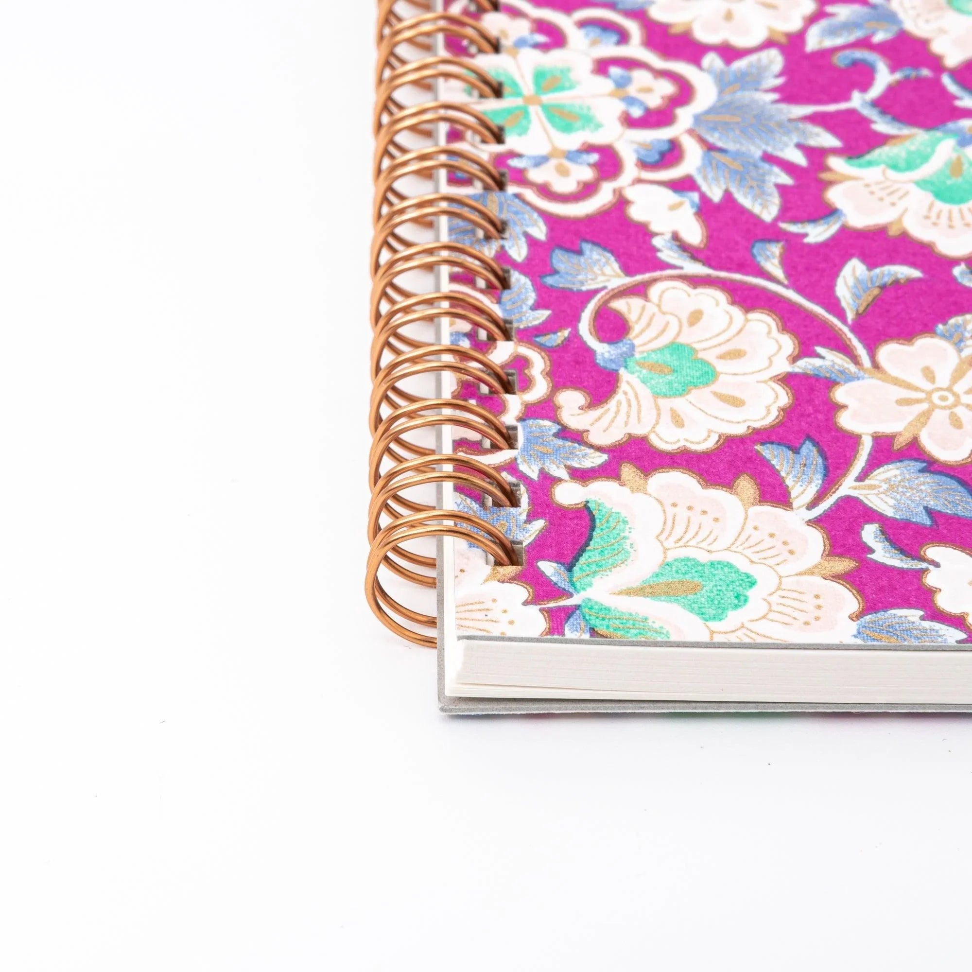 Close-up of the rose gold double spiral binding and top edge of the magenta garden yuzen washi Japanese notebook