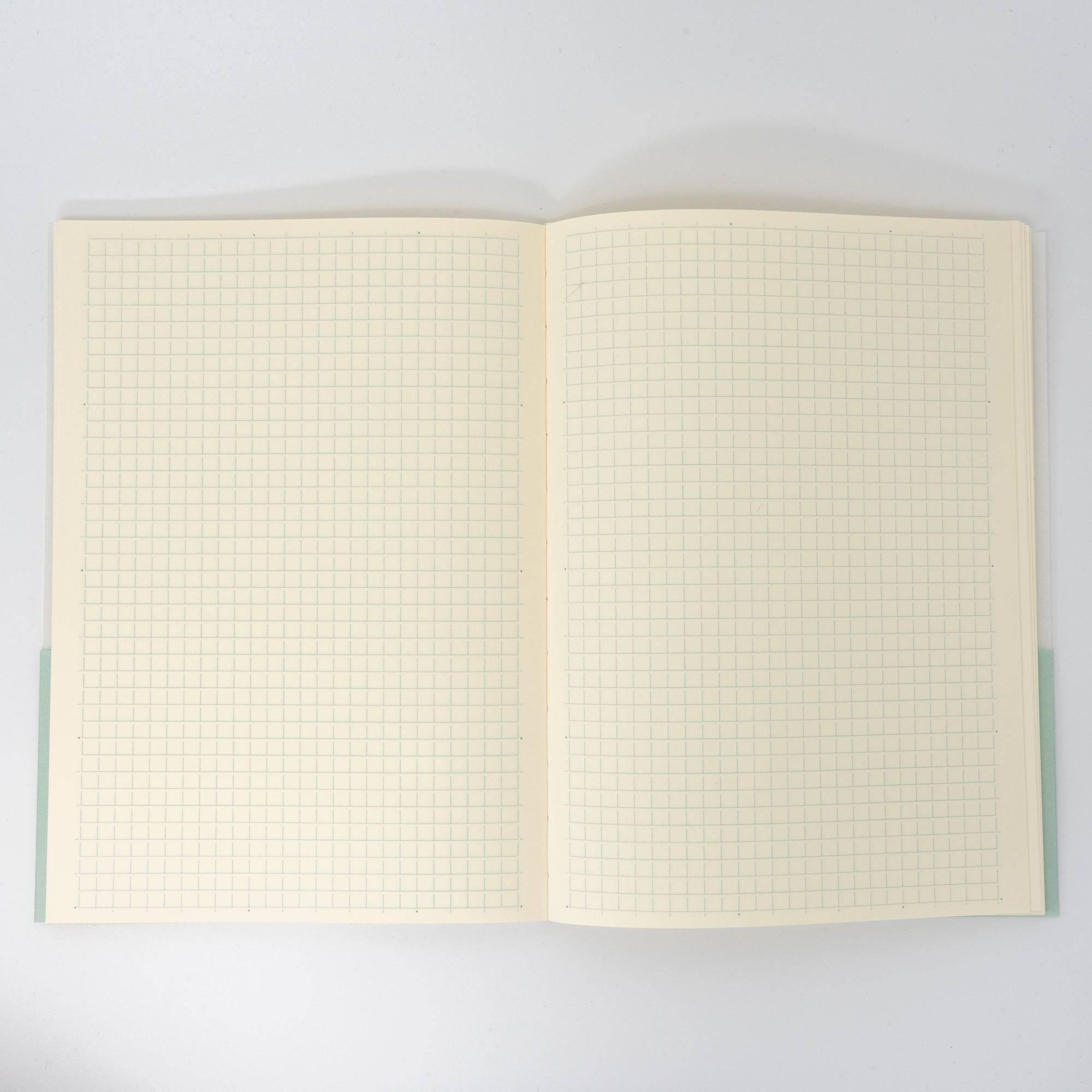 An open Japanese stationery MD Notebook reveals its cream-colored grid pages, perfect for precise writing, sketching, or bullet journaling.