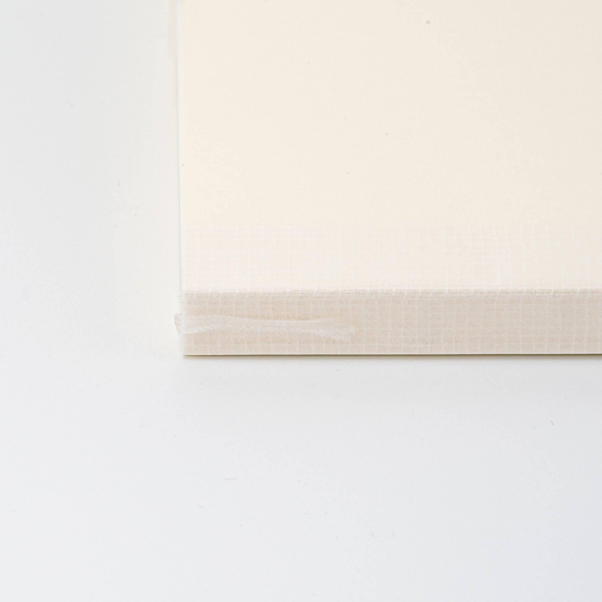 A close-up of the spine of a Japanese stationery MD Notebook, showing its textured binding and minimalist design with subtle beige tones.