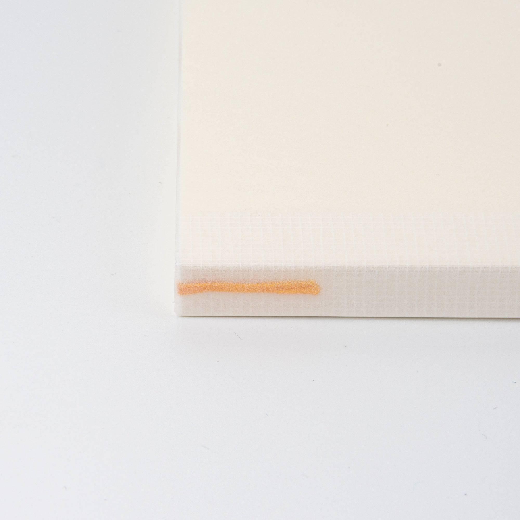A close-up of the spine of a Japanese stationery MD Notebook with an orange bookmark string, highlighting its thoughtful and functional design.