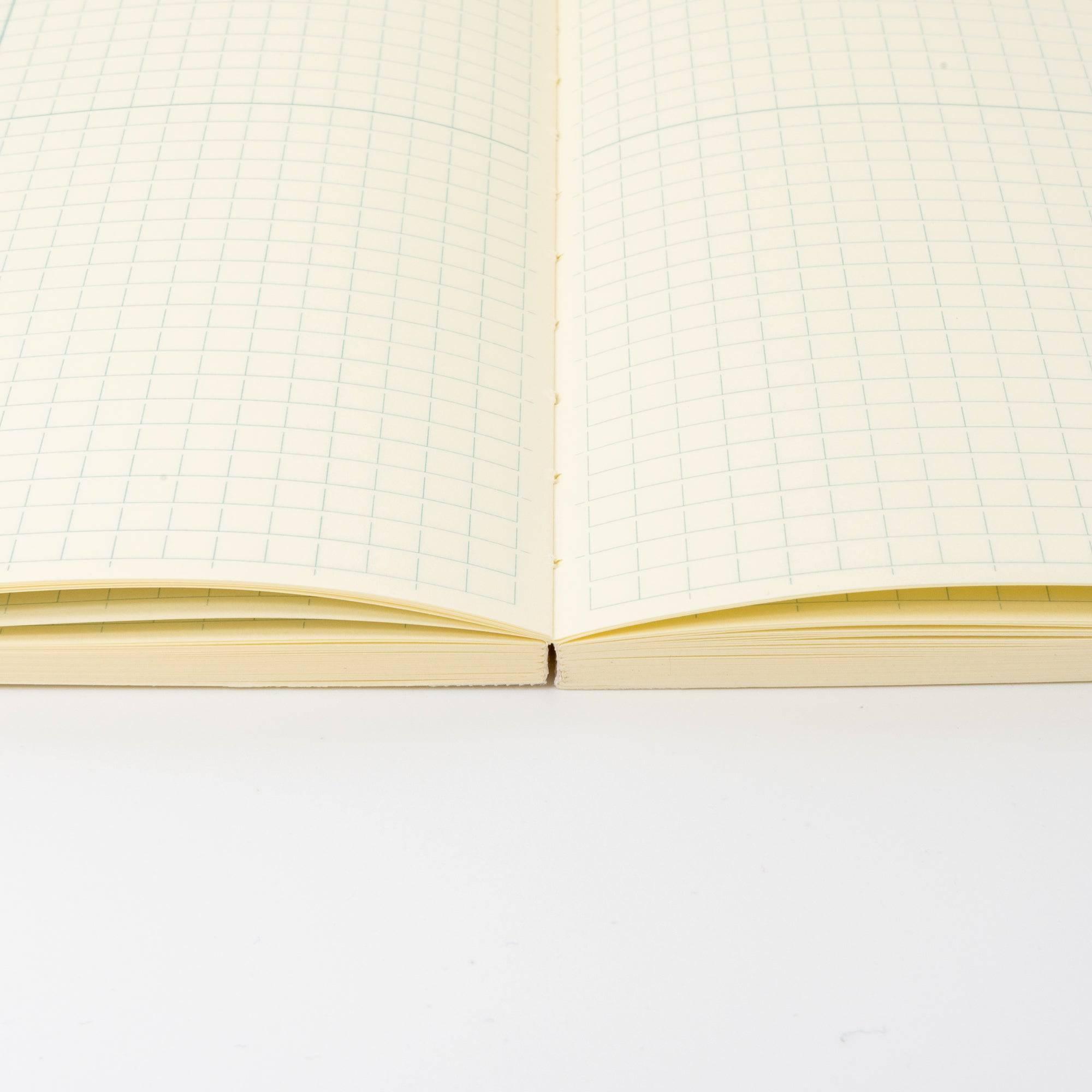 Side view of an MD notebook lying flat, showcasing its high-quality binding in Japanese stationery.