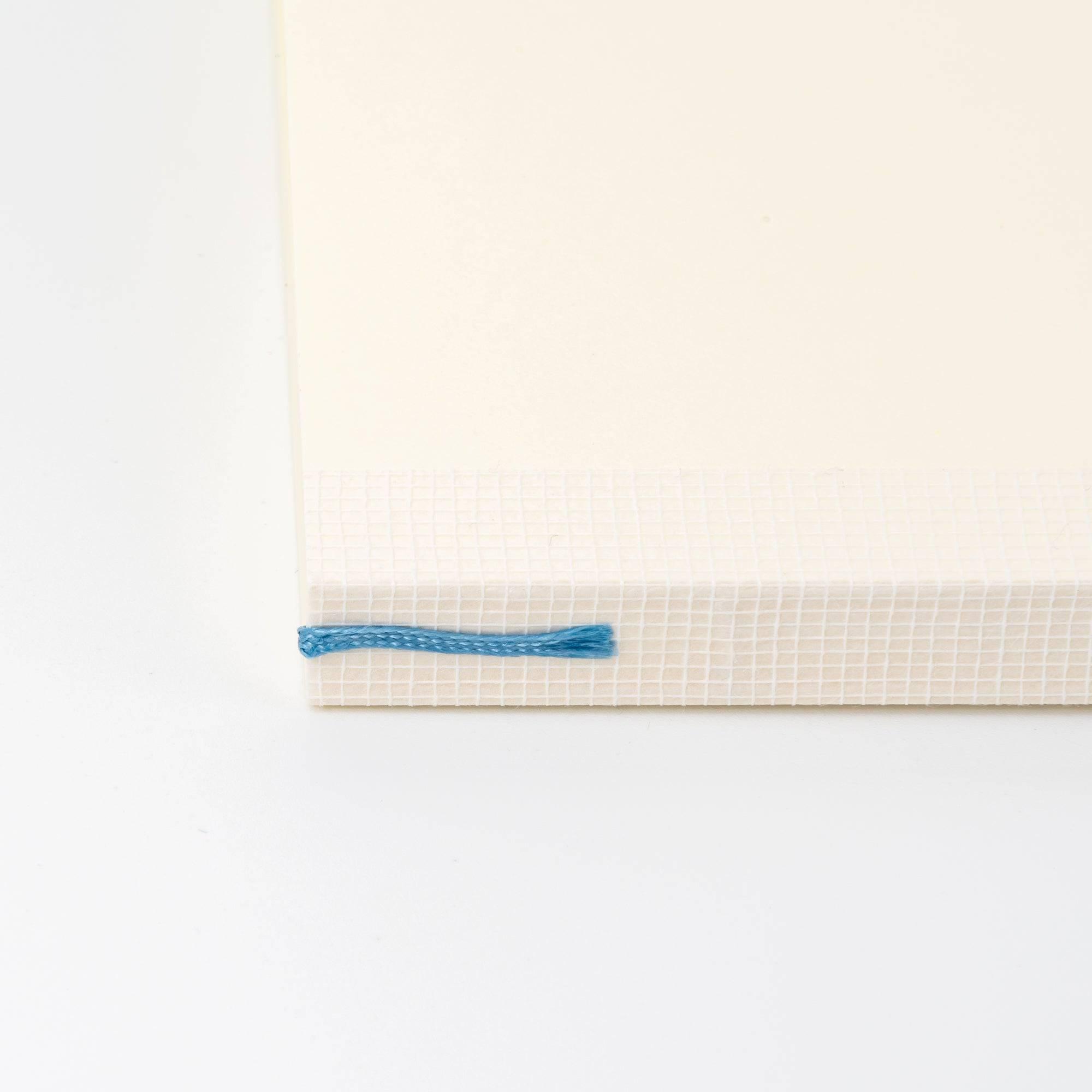 Close-up of an MD notebook spine with blue bookmark, a functional feature in Japanese stationery.