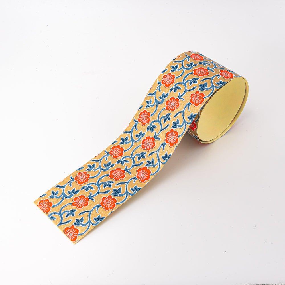 Red Flower yuzen washi tape unrolled showing coral-red blossoms on blue arabesque vine over gold, yellow backing visible