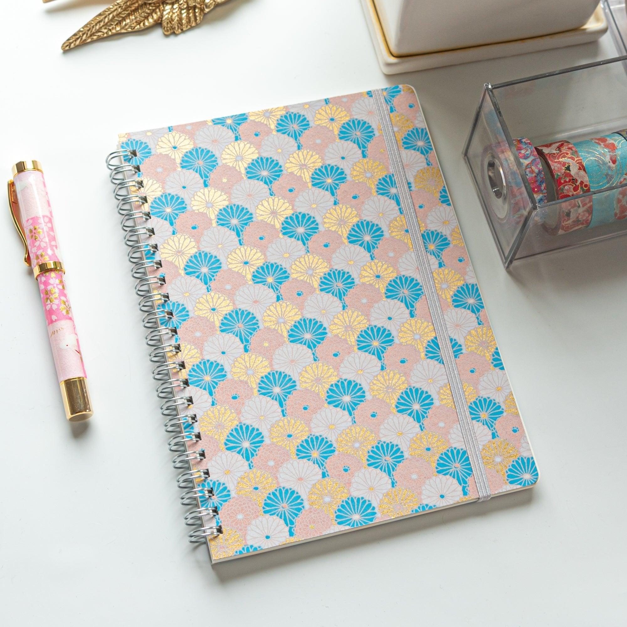 Spiral-bound Japanese notebook with a hand-dyed Yuzen washi cover, featuring fan-shaped patterns in blue, gold, and pink, showcasing Japanese stationery craftsmanship.