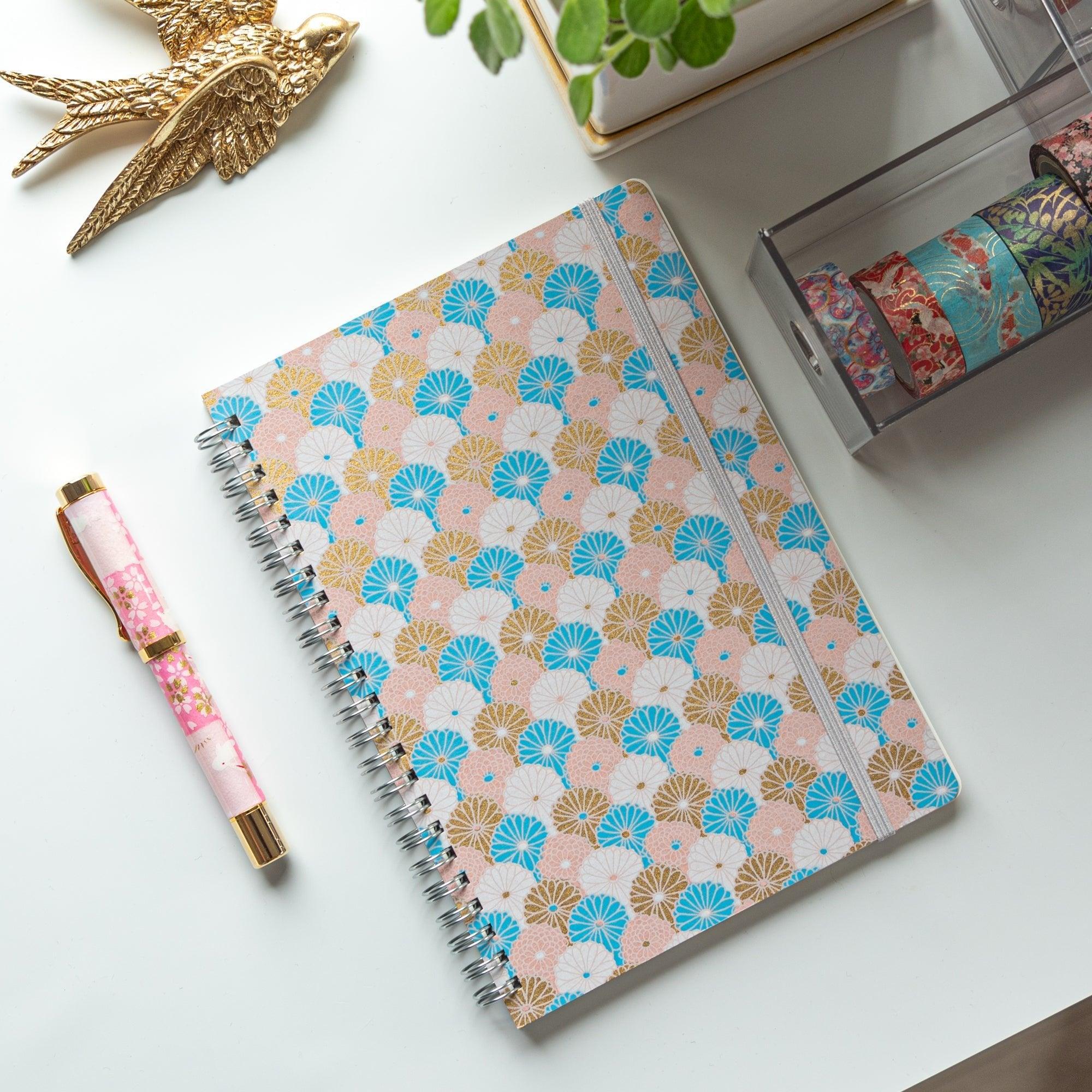 Spiral-bound Japanese notebook with a hand-dyed Yuzen washi cover, featuring fan-shaped patterns in blue, gold, and pink, showcasing Japanese stationery craftsmanship.