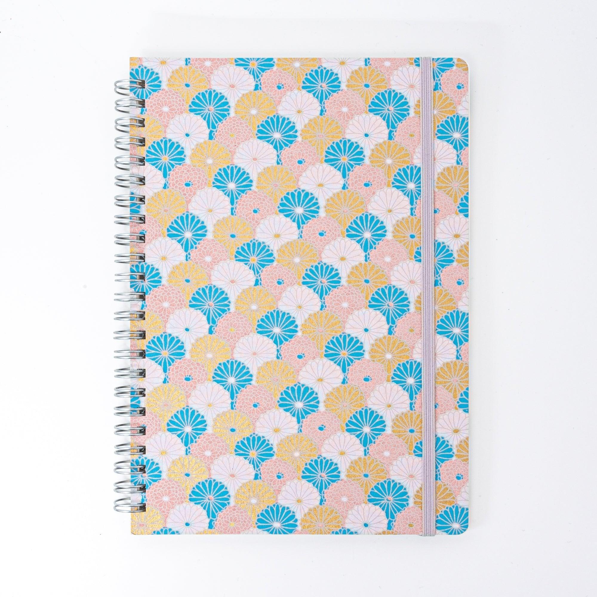 Spiral-bound Japanese notebook with a hand-dyed Yuzen washi cover, featuring fan-shaped patterns in blue, gold, and pink, showcasing Japanese stationery craftsmanship.