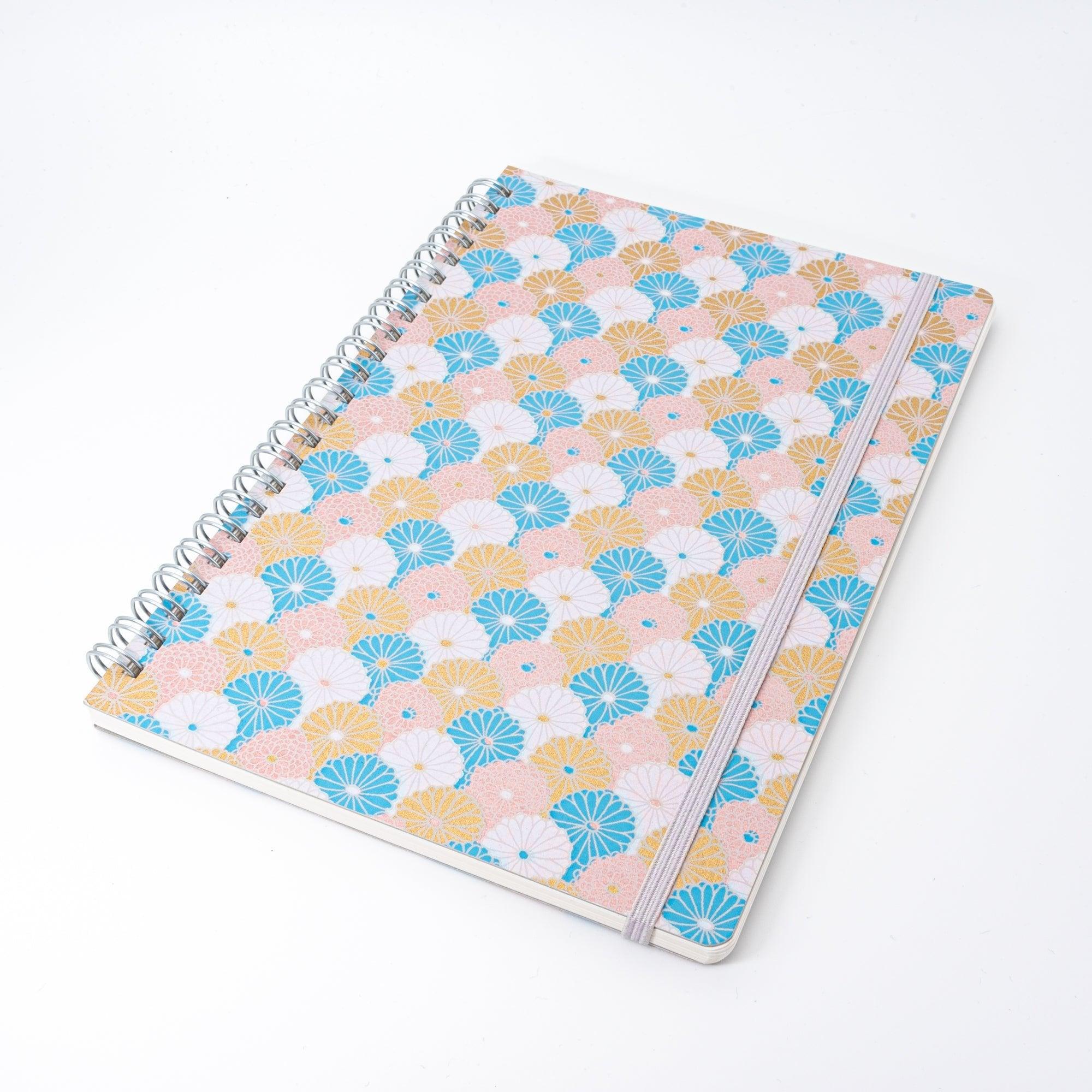 Spiral-bound Japanese notebook with a hand-dyed Yuzen washi cover, featuring fan-shaped patterns in blue, gold, and pink, showcasing Japanese stationery craftsmanship.