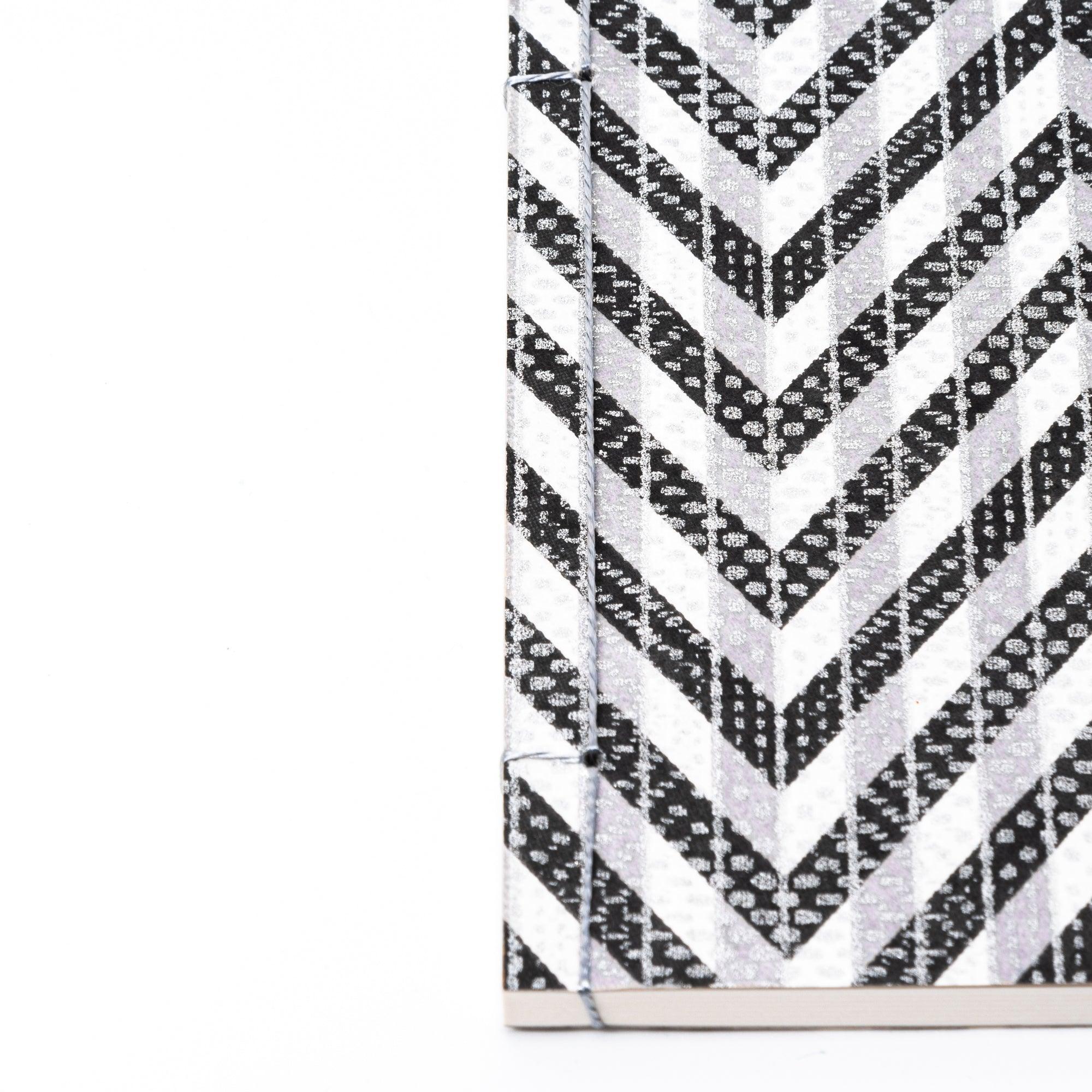 Notebook with a black and gray chevron-patterned cover, screenprinted by hand. Features bleed-proof paper for smooth writing. Made in Japan.
