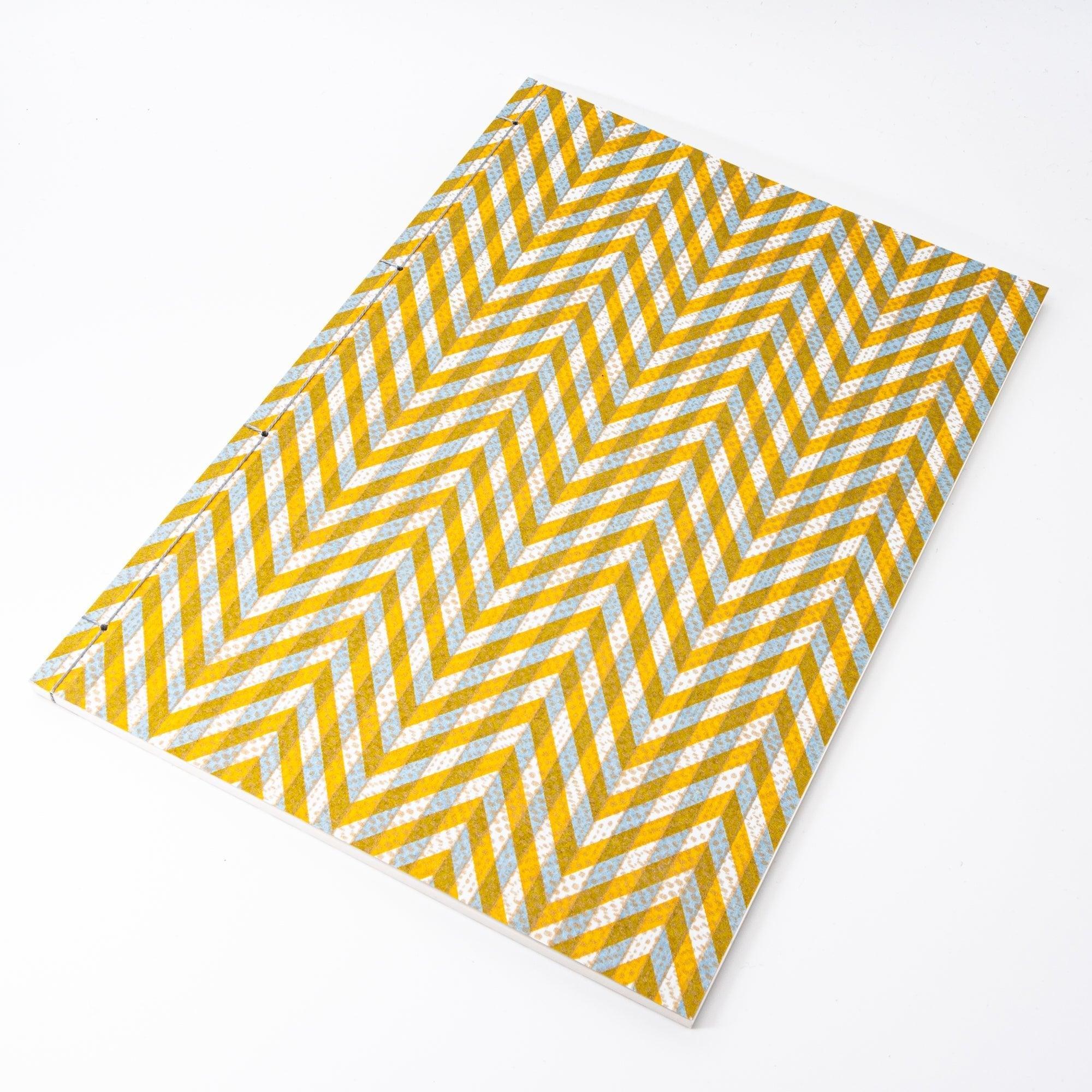 Notebook with a yellow and gray chevron-patterned cover, screenprinted by hand. Features bleed-proof paper for smooth writing. Made in Japan.
