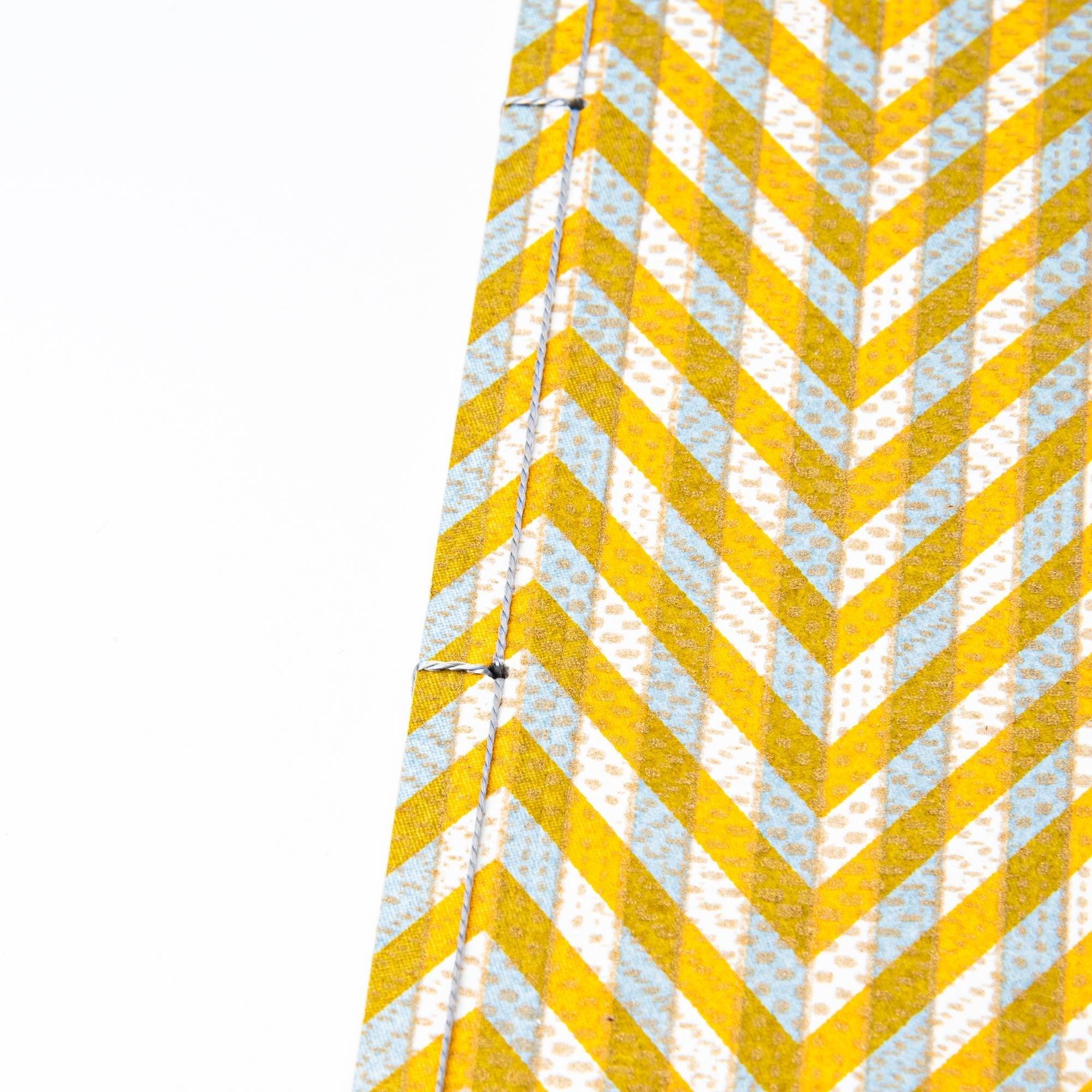 Notebook with a yellow and gray chevron-patterned cover, screenprinted by hand. Features bleed-proof paper for smooth writing. Made in Japan.