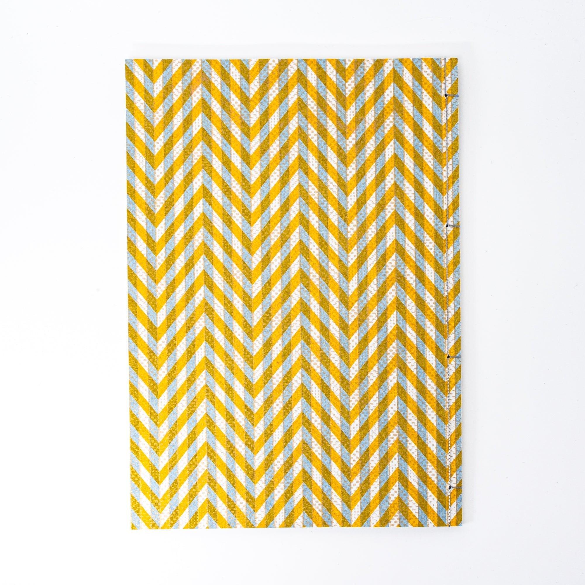 Notebook with a yellow and gray chevron-patterned cover, screenprinted by hand. Features bleed-proof paper for smooth writing. Made in Japan.