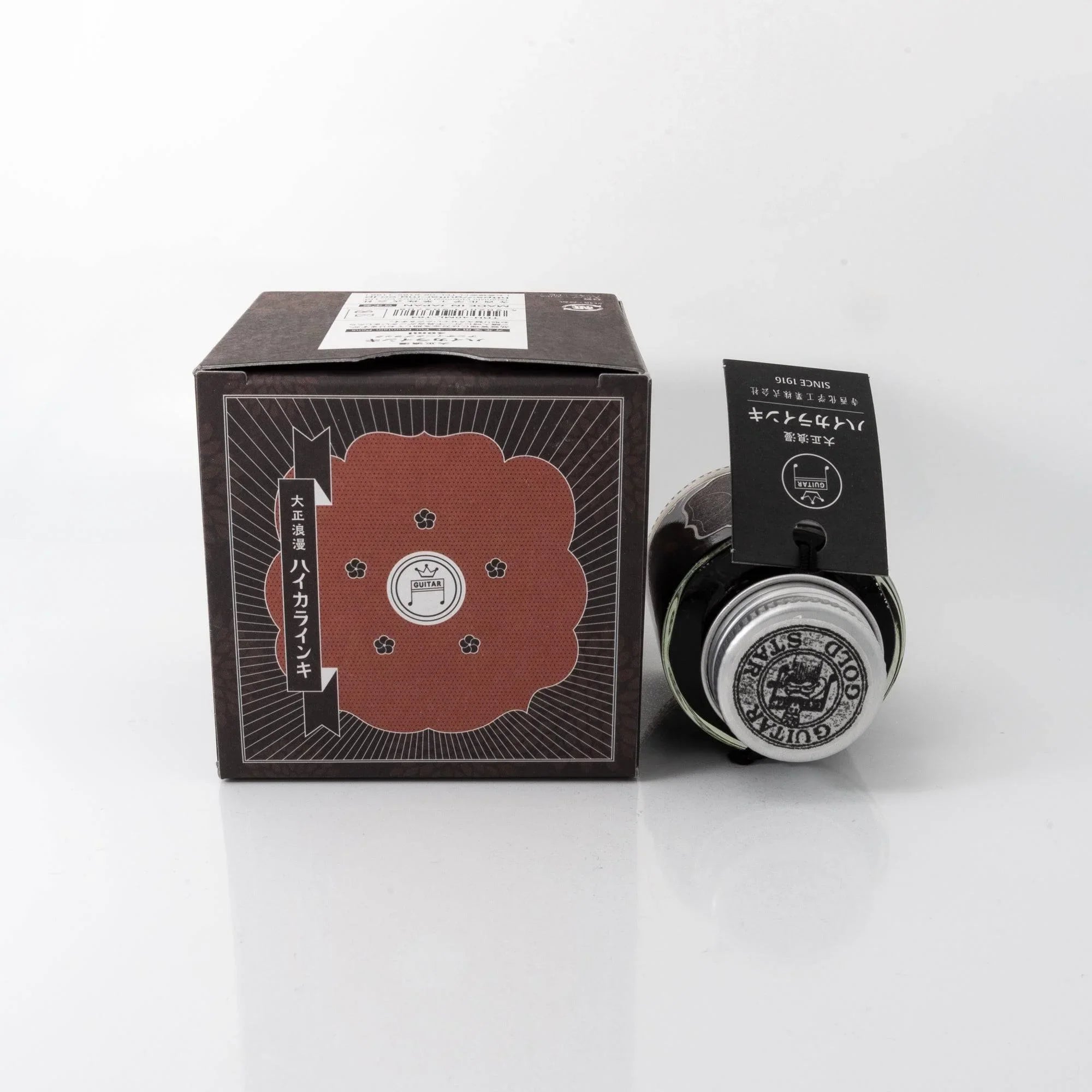 Close-up detail of Taisho Romance Antique Black fountain pen ink glass bottle showing metal cap and label