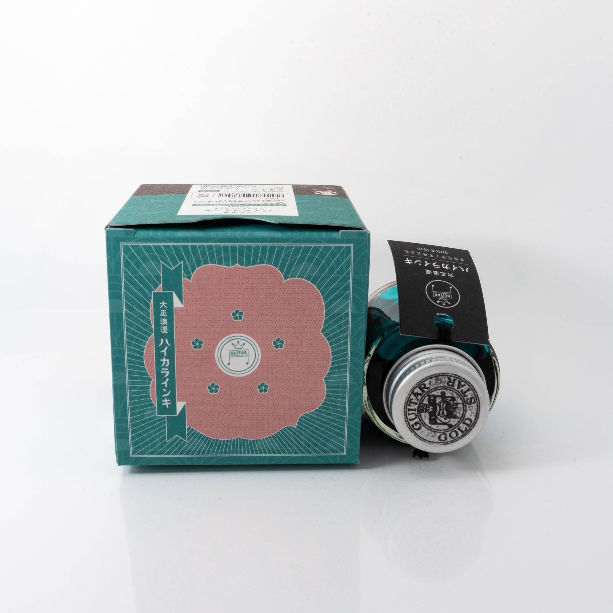 Taisho Romance Brilliant Mint fountain pen ink bottle and matching pen, arranged on a wooden desk, emphasizing classic design.