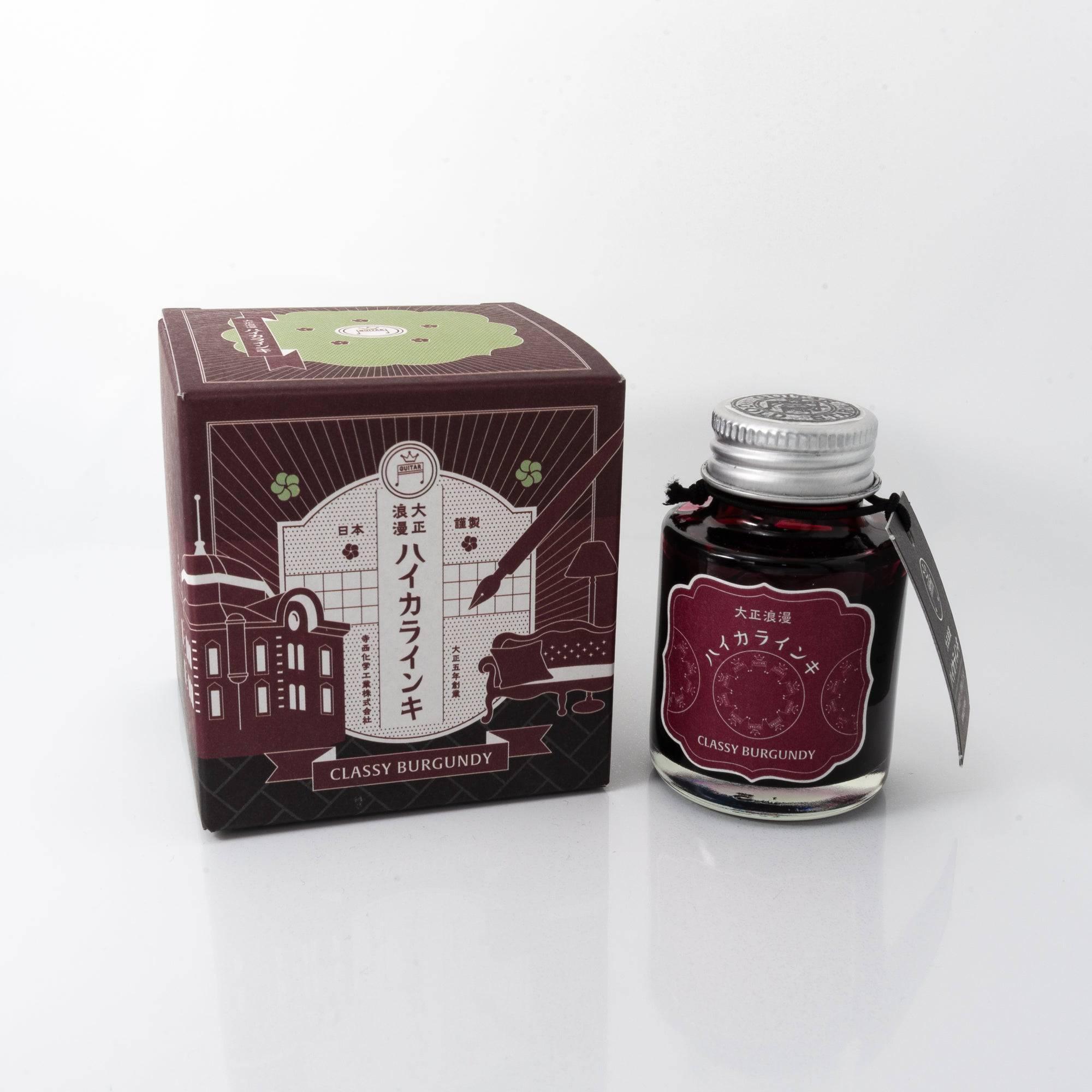 Taisho Romance Classy Burgundy fountain pen ink bottle with a deep burgundy hue, placed on a wooden desk under soft natural light.