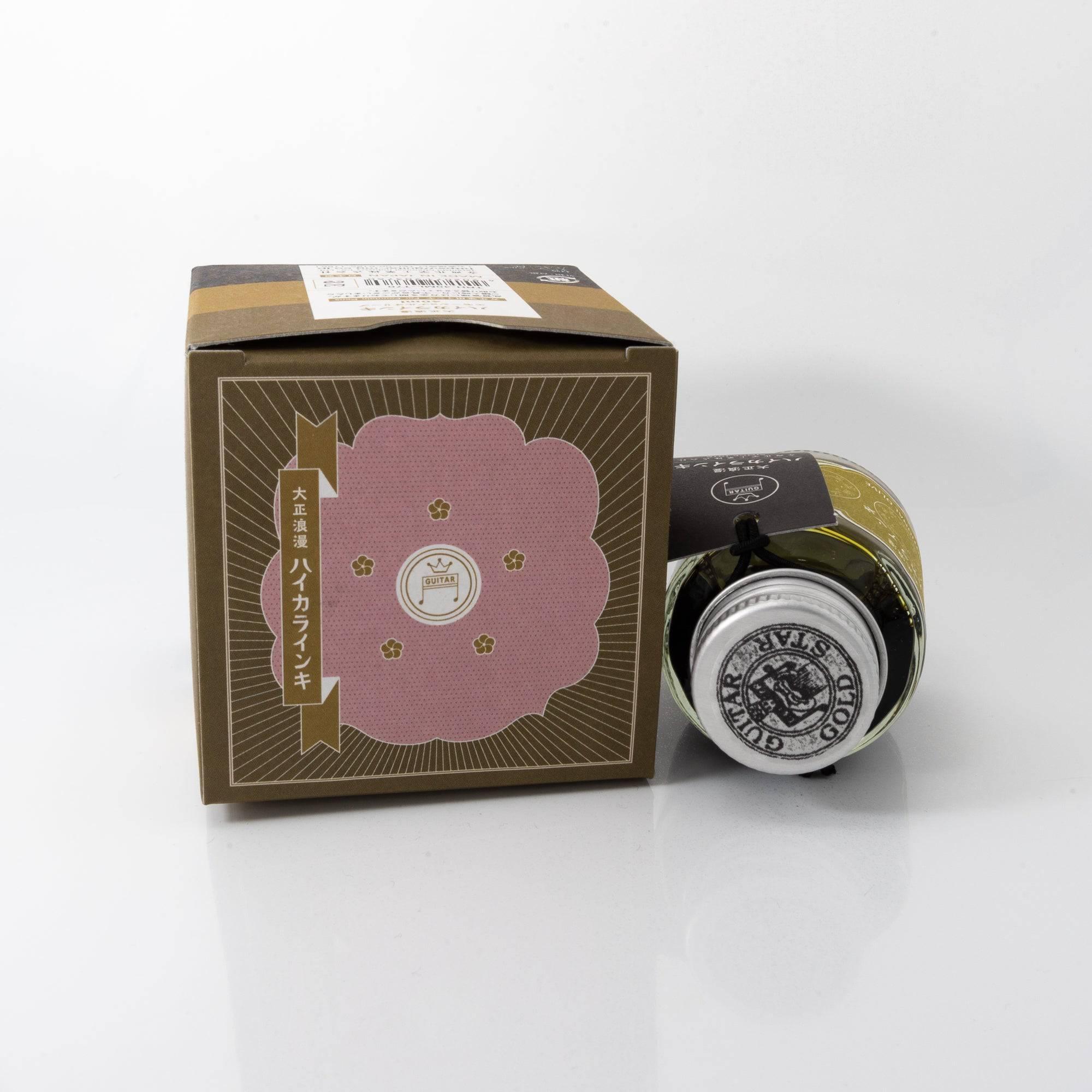 Taisho Romance Emotional Olive fountain pen ink bottle and matching pen, arranged on a wooden desk, emphasizing a classic design.