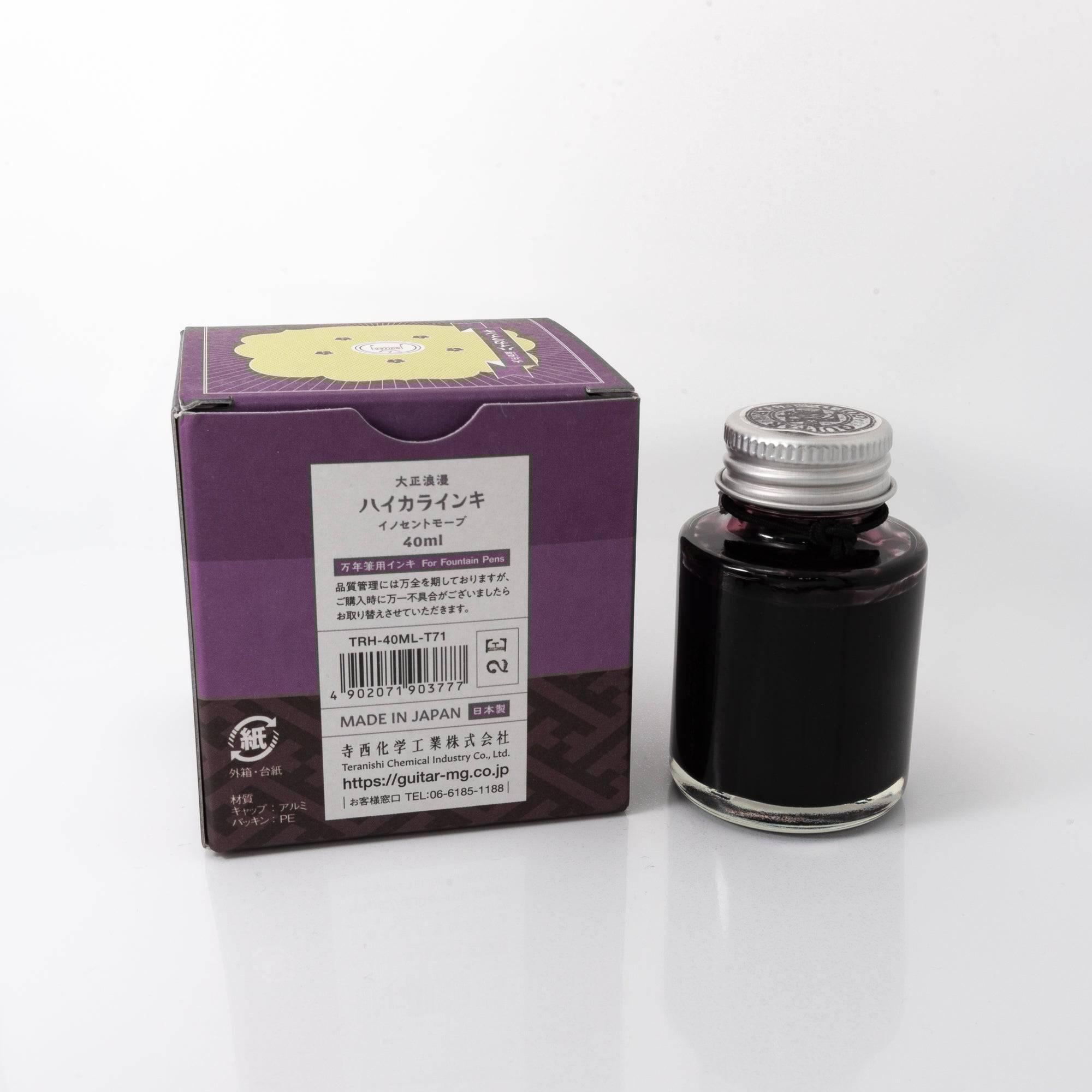 Top view of the Taisho Romance Innocent Mauve ink bottle, highlighting its muted mauve ink, surrounded by natural wooden tones.