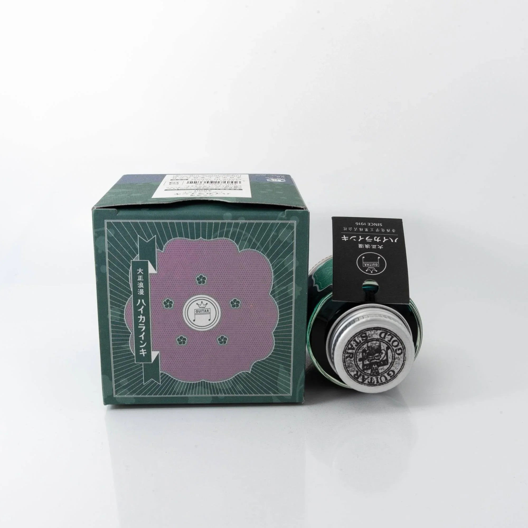 Close-up detail of Taisho Romance Lady Emerald fountain pen ink glass bottle showing metal cap and label