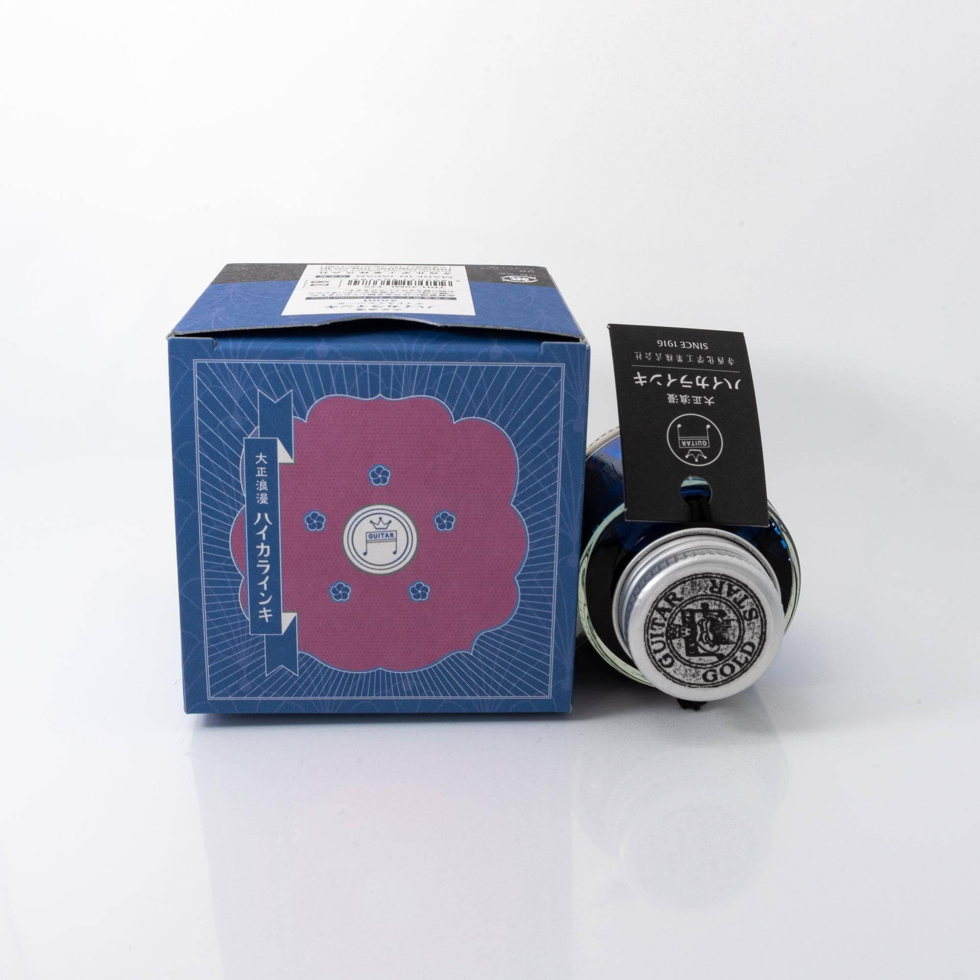 Taisho Romance Nighttime Soda fountain pen ink bottle and matching pen, arranged on a wooden desk, emphasizing elegant design.