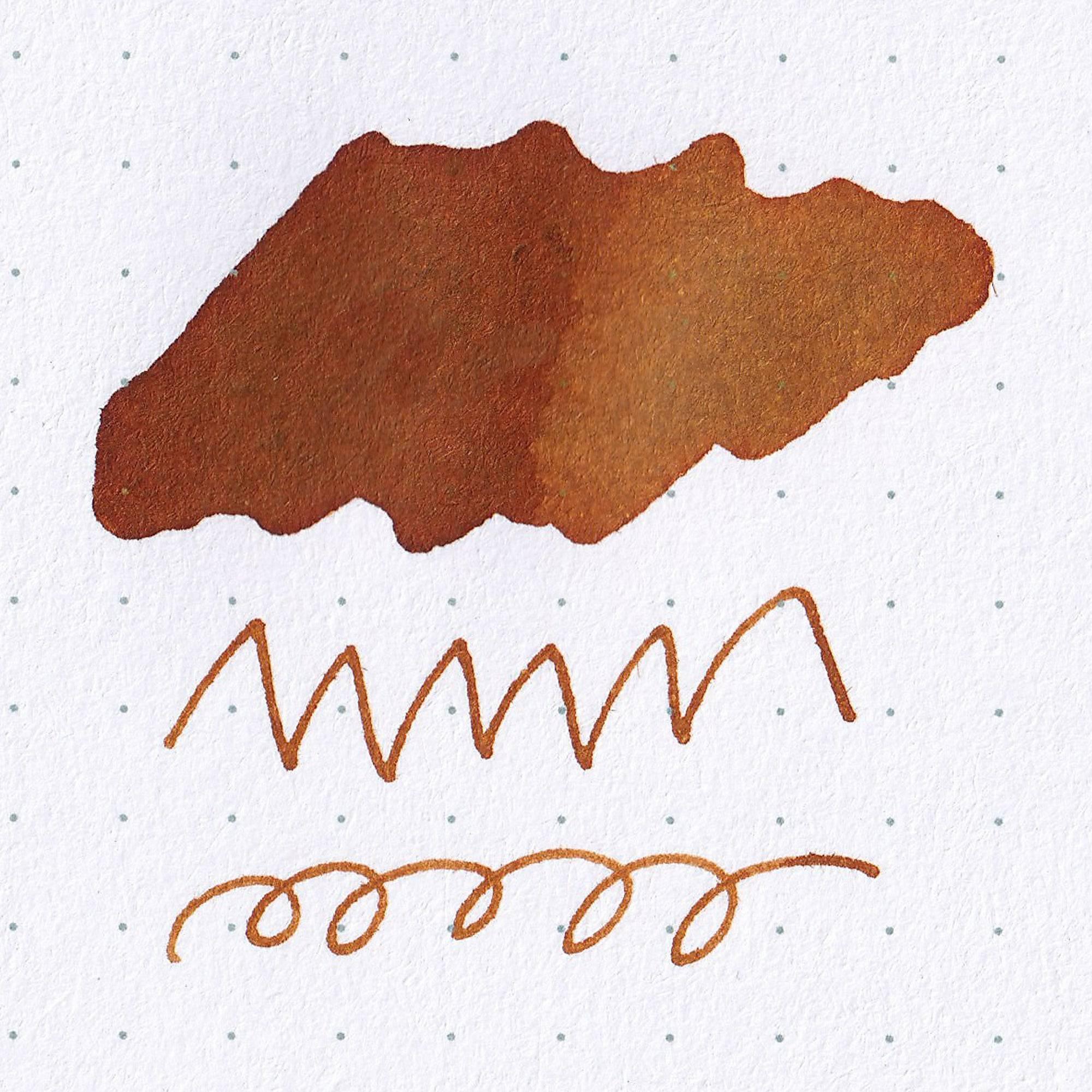 A swatch of "NOSTALGIC HONEY" ink on dotted paper, showcasing warm brown tones and smooth line variations, part of Japanese stationery.