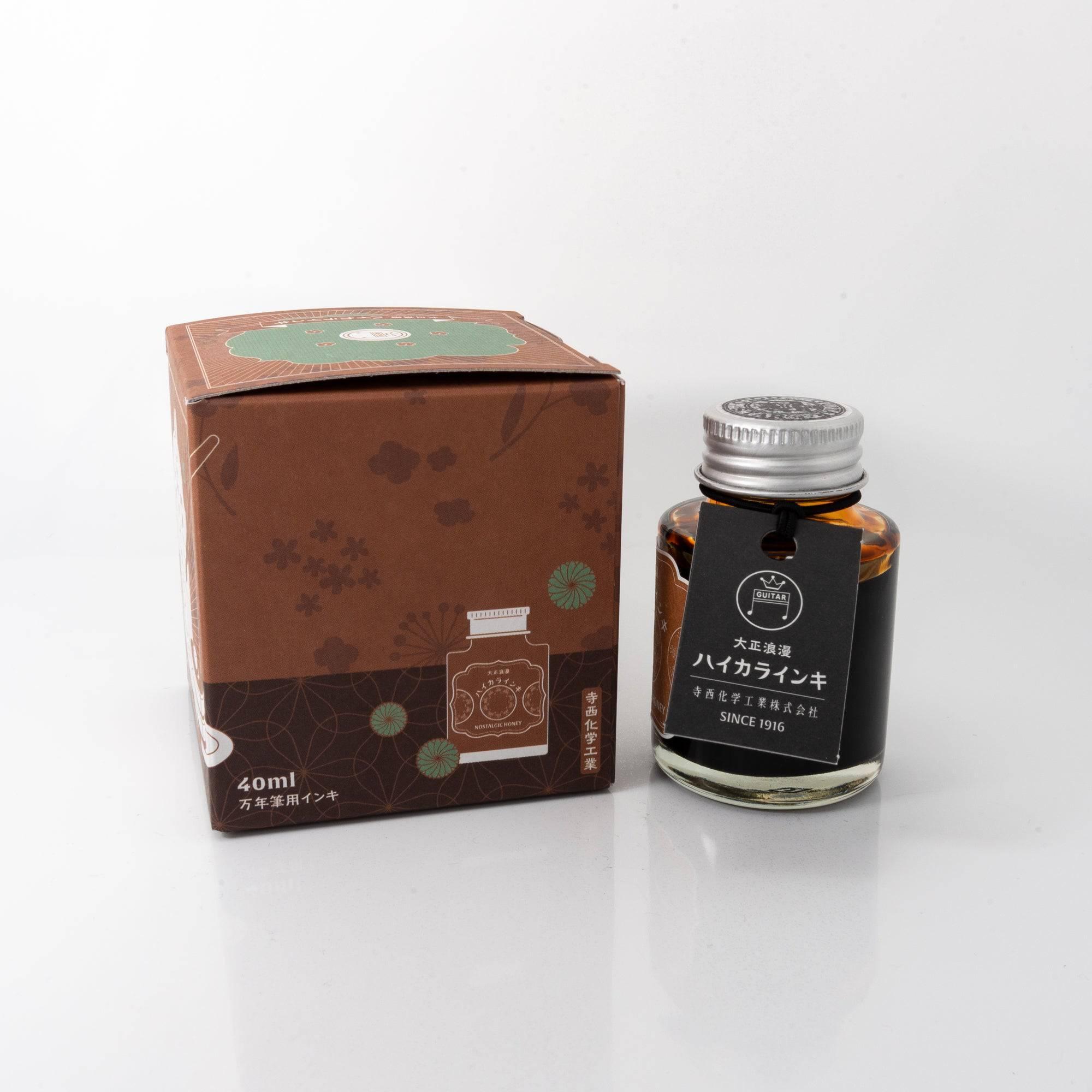 A bottle of "NOSTALGIC HONEY" ink with its box, featuring a vintage design and elegant details, a classic Japanese stationery item.