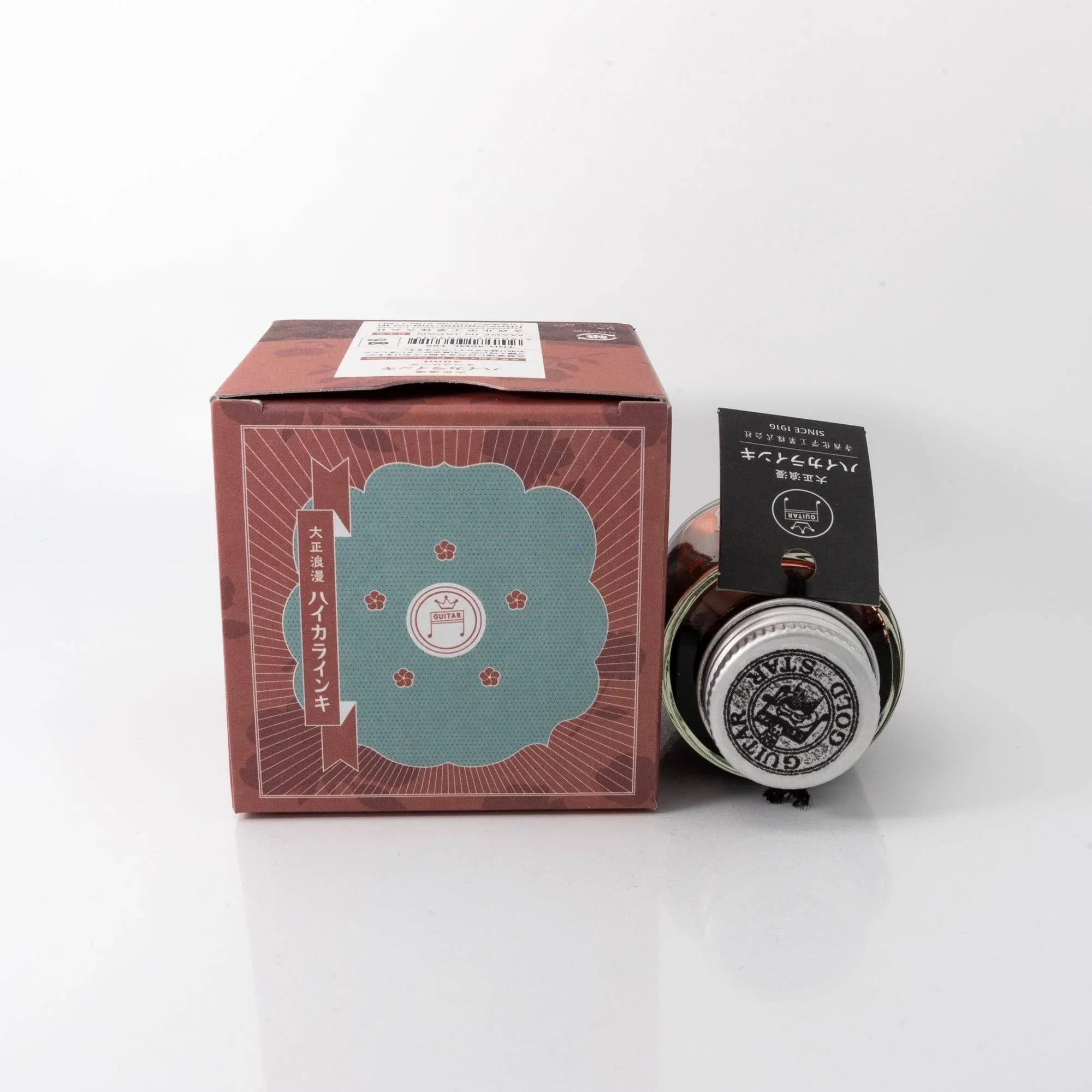 Close-up detail of Taisho Romance Opera Rose fountain pen ink glass bottle showing metal cap and label