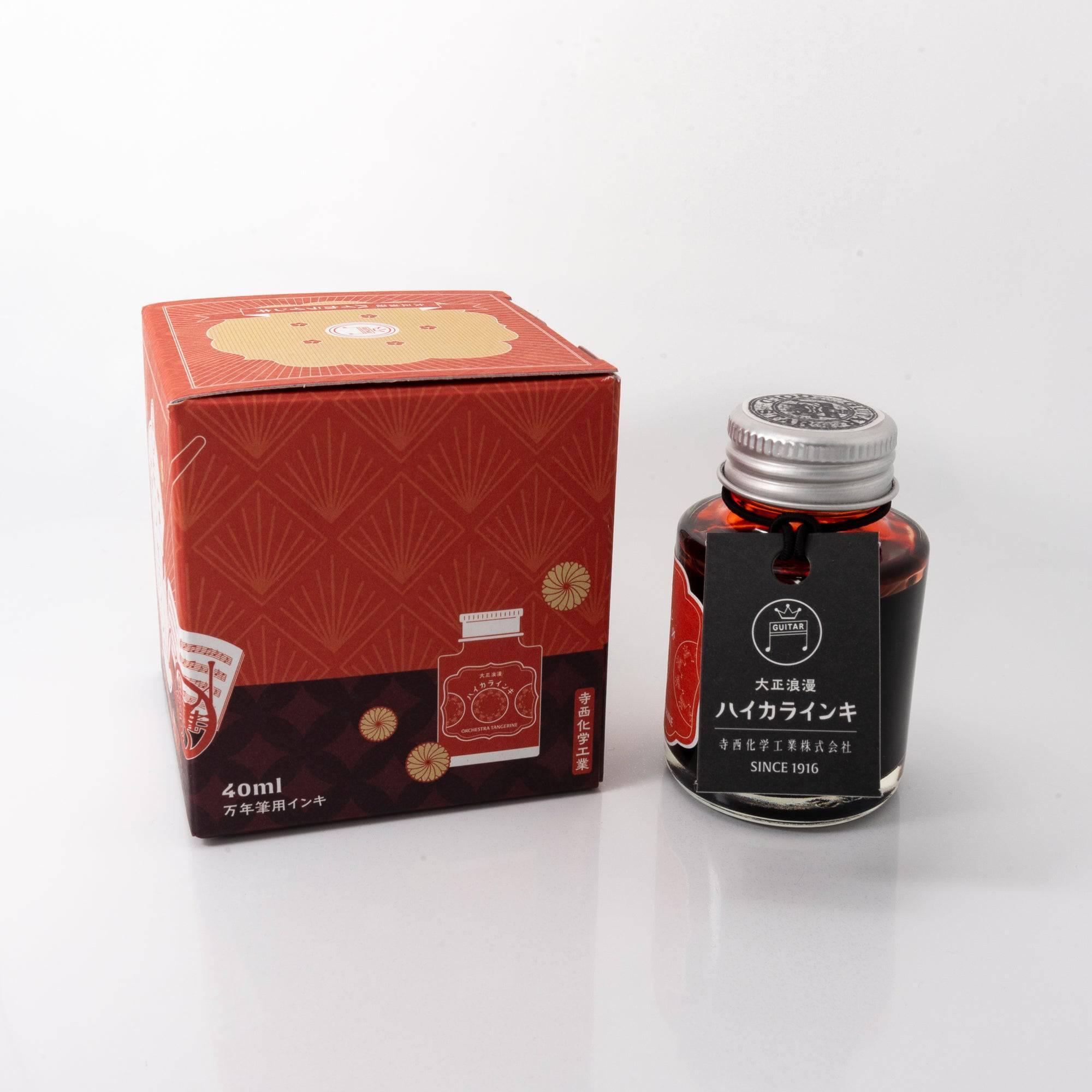 Open Taisho Romance Orchestra Tangerine ink bottle with bold orange liquid, placed beside a fountain pen, blending style and functionality.