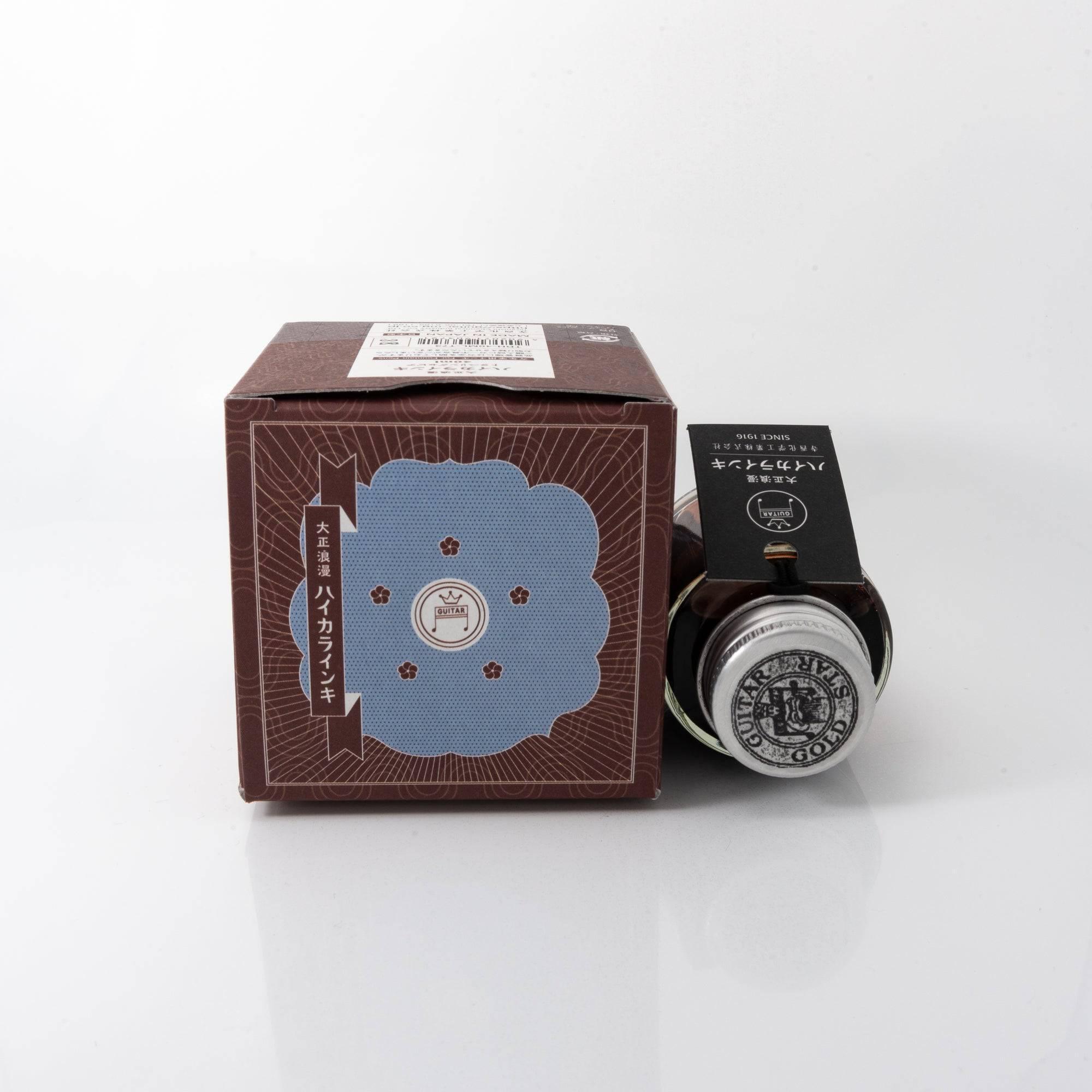 Taisho Romance Traveling Sepia fountain pen ink bottle and matching pen, arranged on a wooden desk, emphasizing classic design.