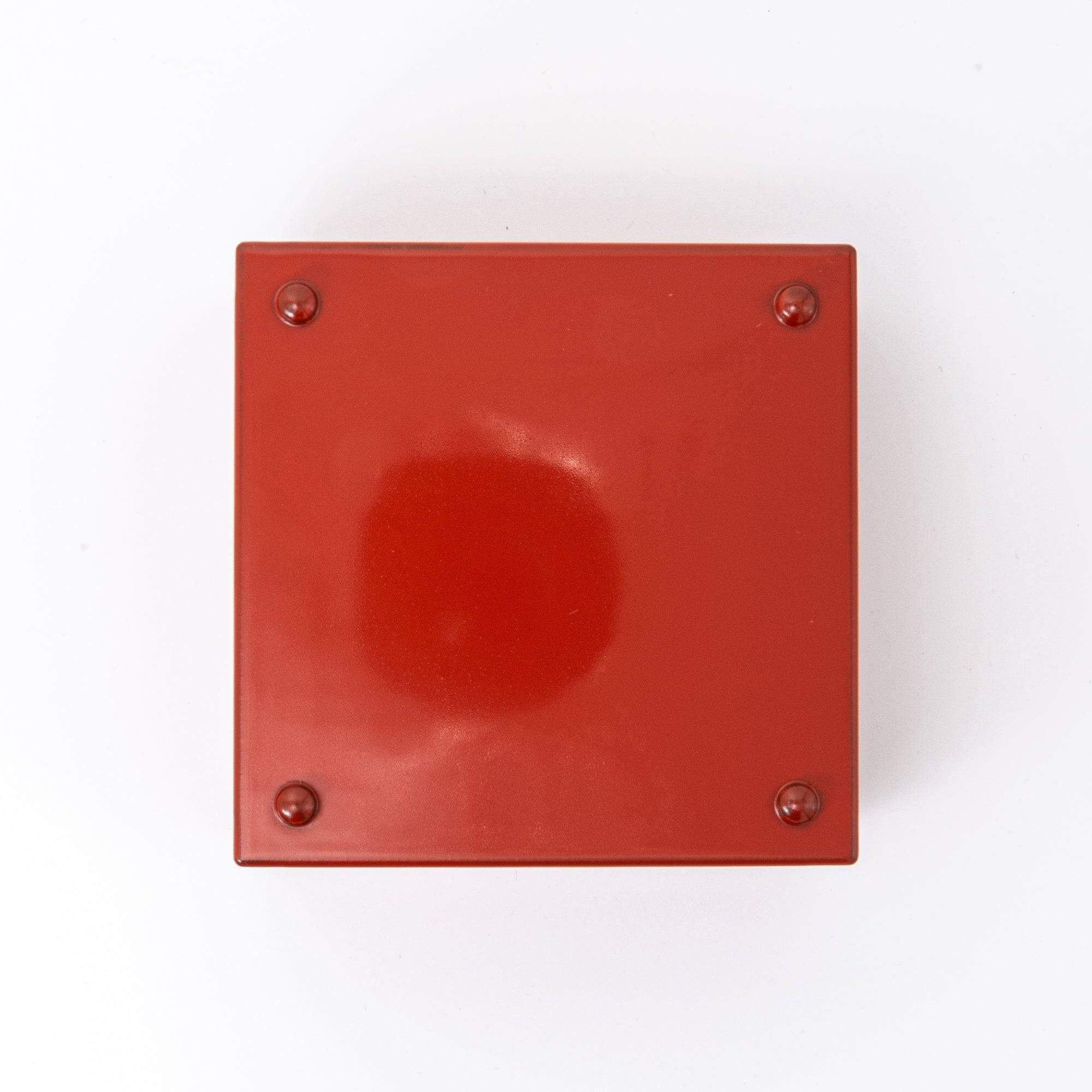 Bottom view of a red Japanese lacquer stationery box with a plain glossy surface and four small support pads, displayed against a clean white background.