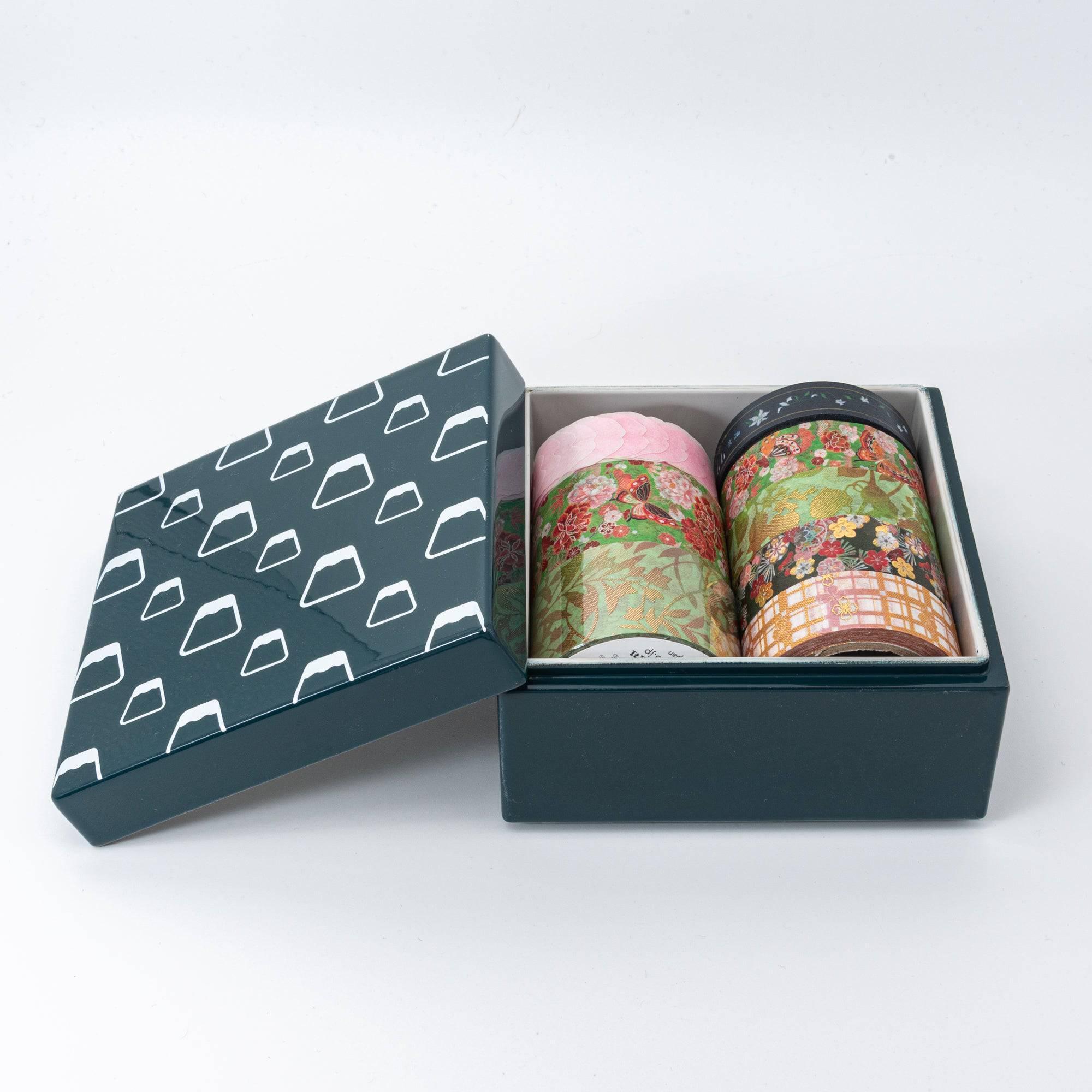 Open green Japanese lacquer stationery box with white Mount Fuji patterns, holding multiple colorful washi tape rolls, placed against a white background.