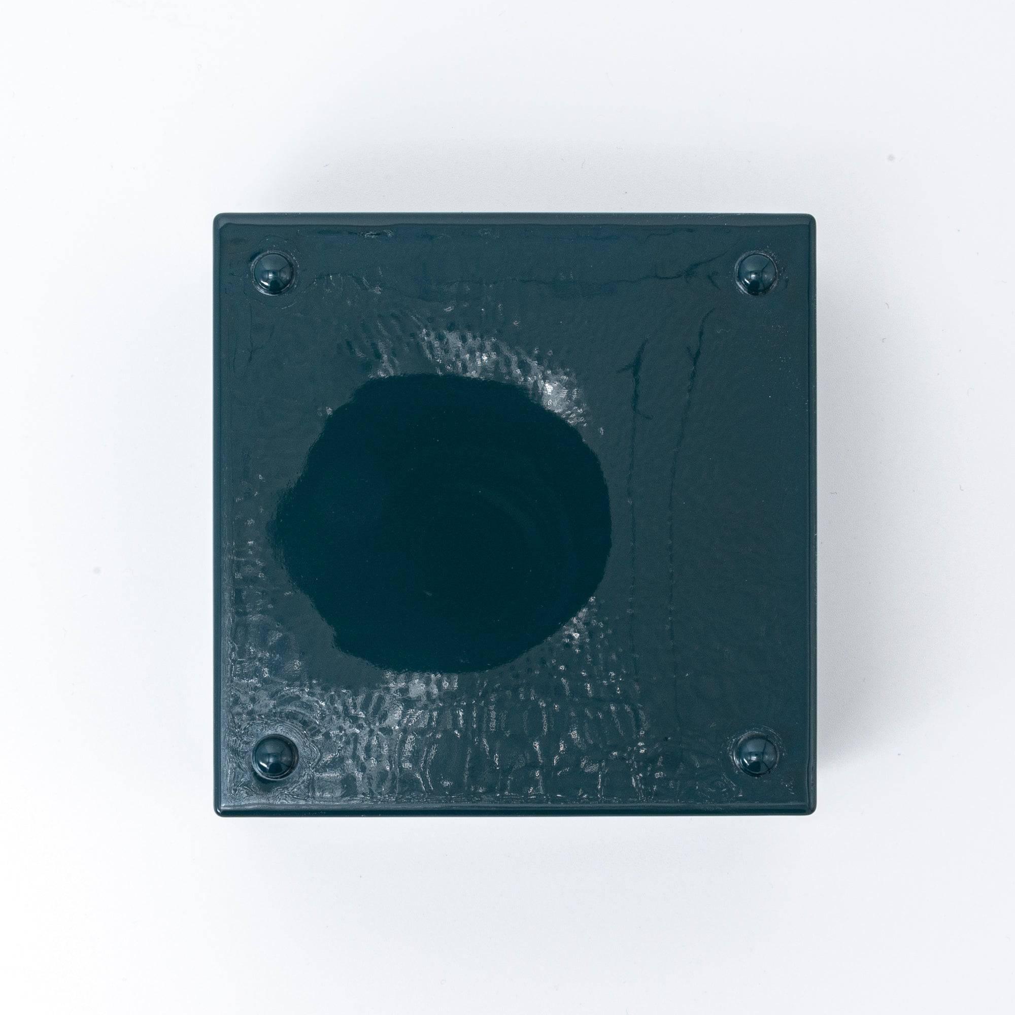 Bottom view of a green Japanese lacquer stationery box, featuring a plain glossy finish and four small support pads, placed against a white background.