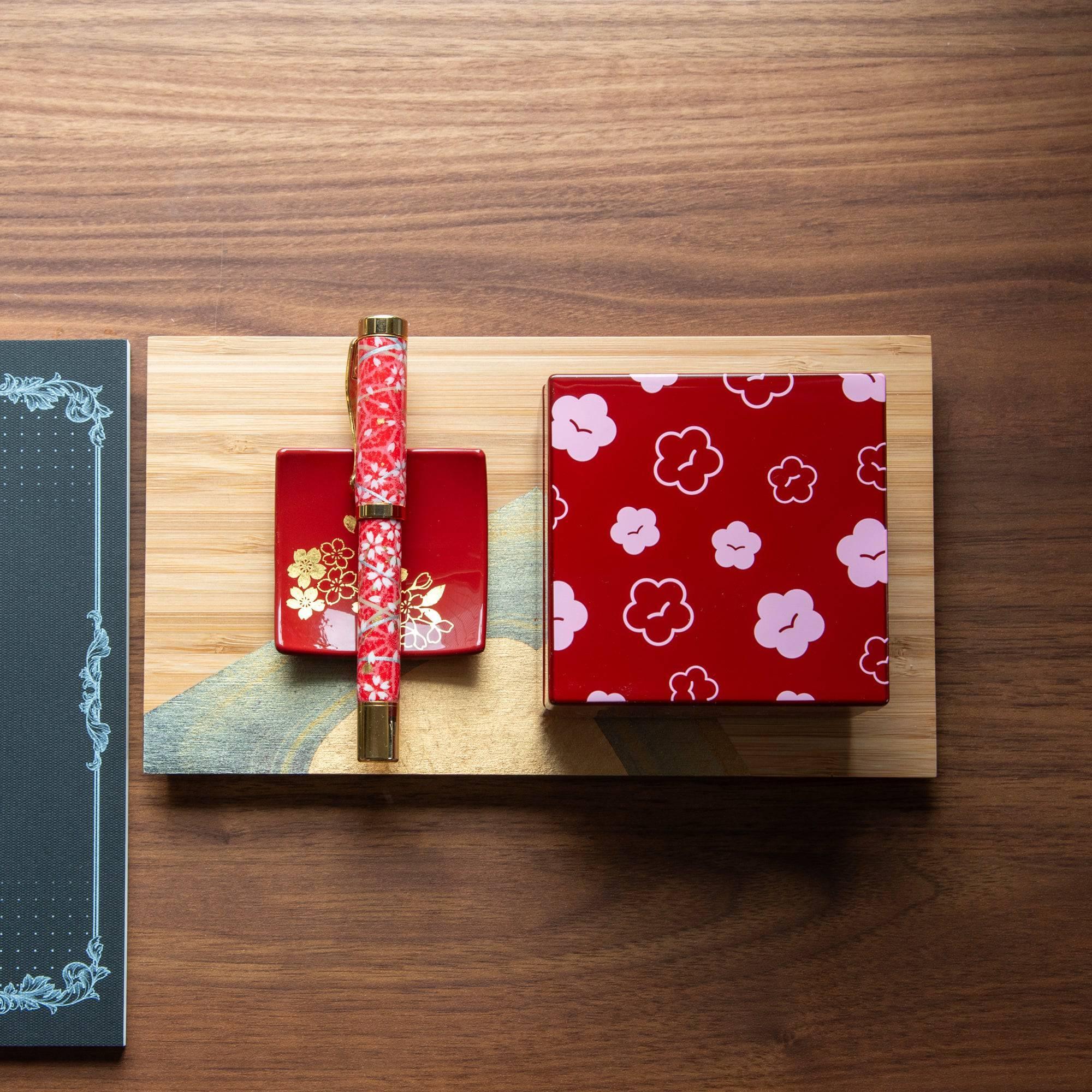 Japanese urushi kohako plum lacquer trinket box at three-quarter angle, burgundy with pink outlined flower blossoms