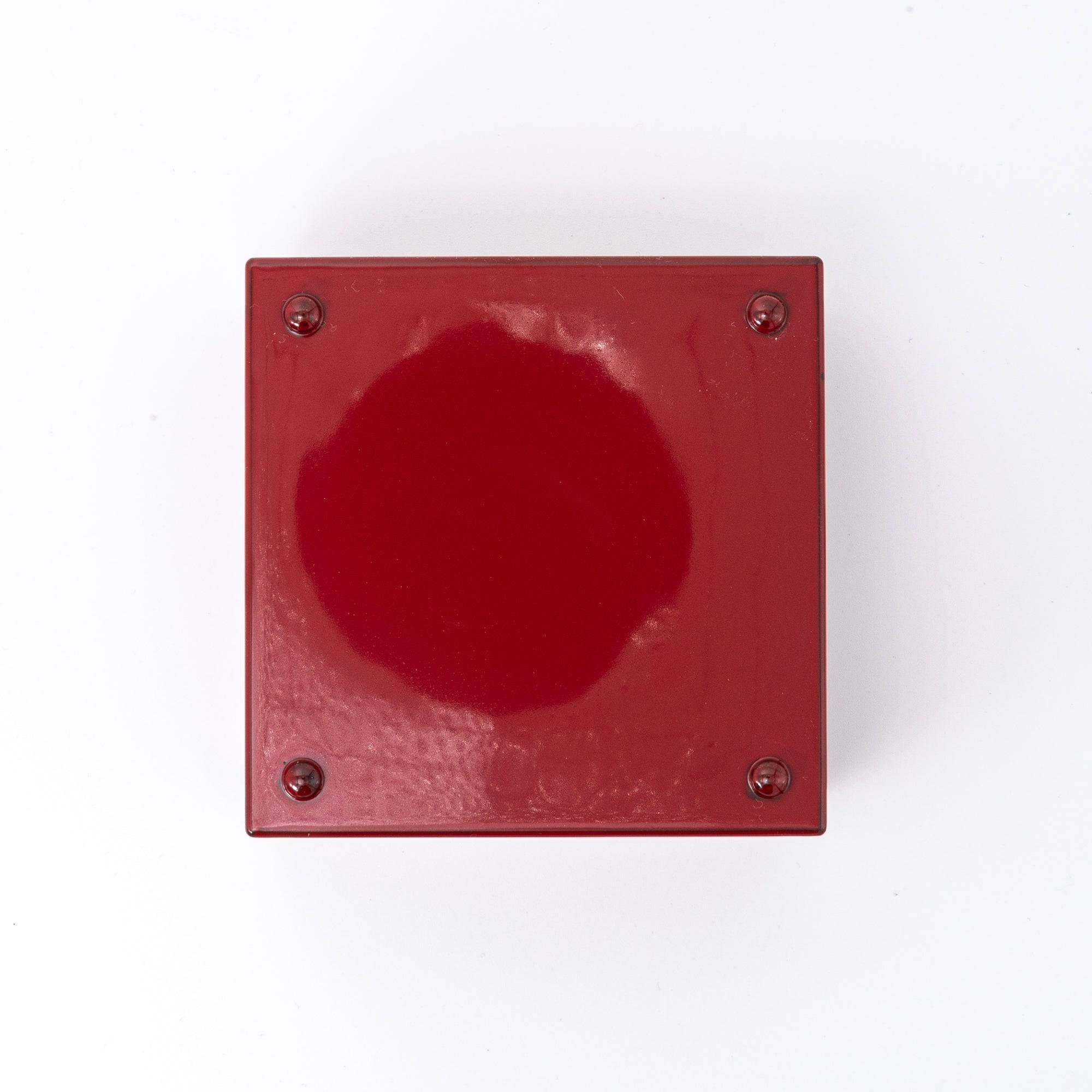 Bottom view of a red Japanese lacquer stationery box with a plain glossy finish and four small support pads, placed against a white background.