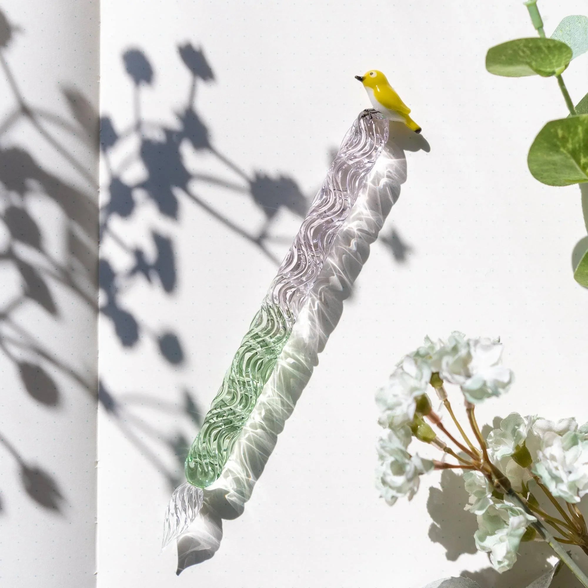 White-eye glass dip pen close-up showing fine calligraphy nib with green and white colored glass body with holder