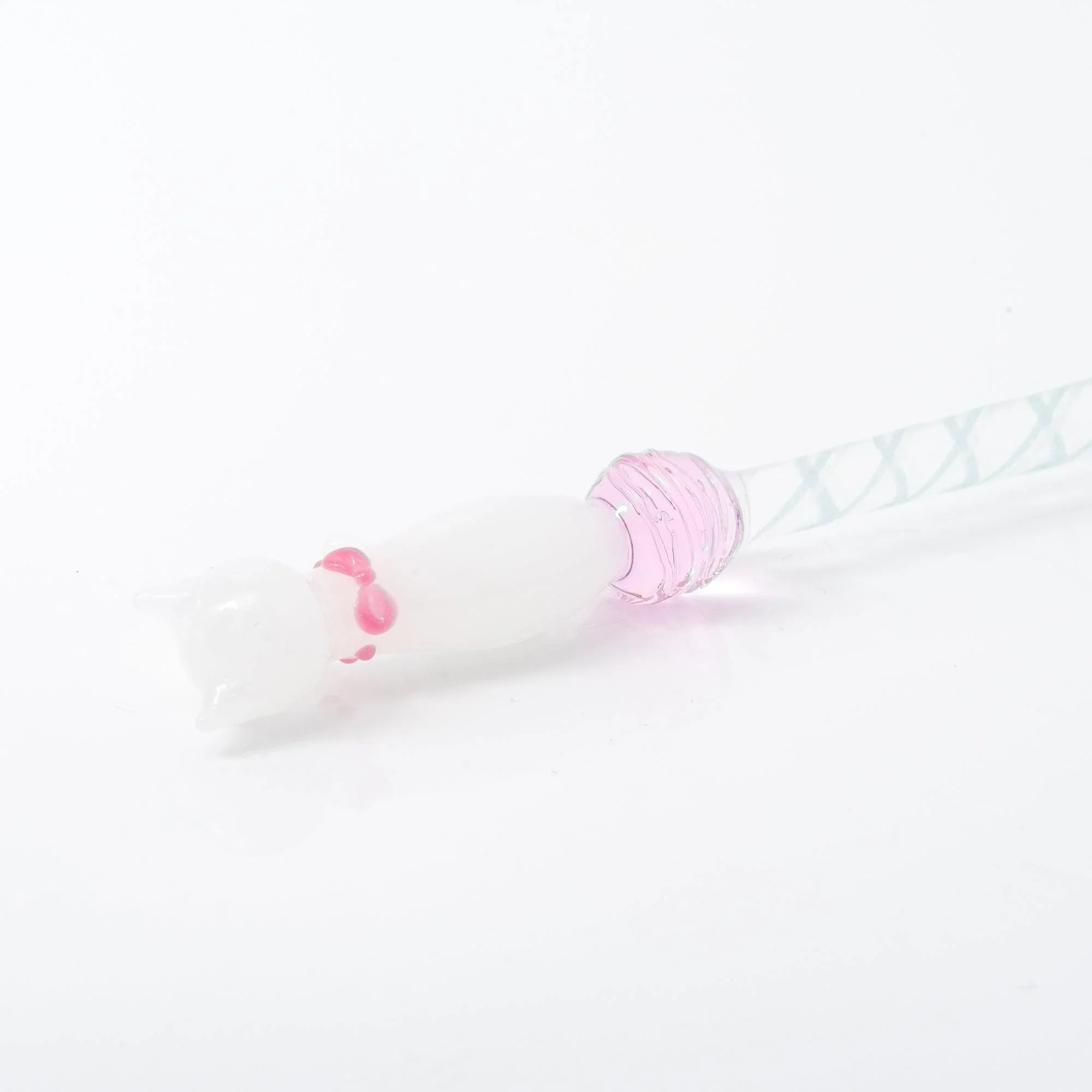 White sitting cat Nyanko on transparent glass dip pen handle with spiral texture detail visible closeup