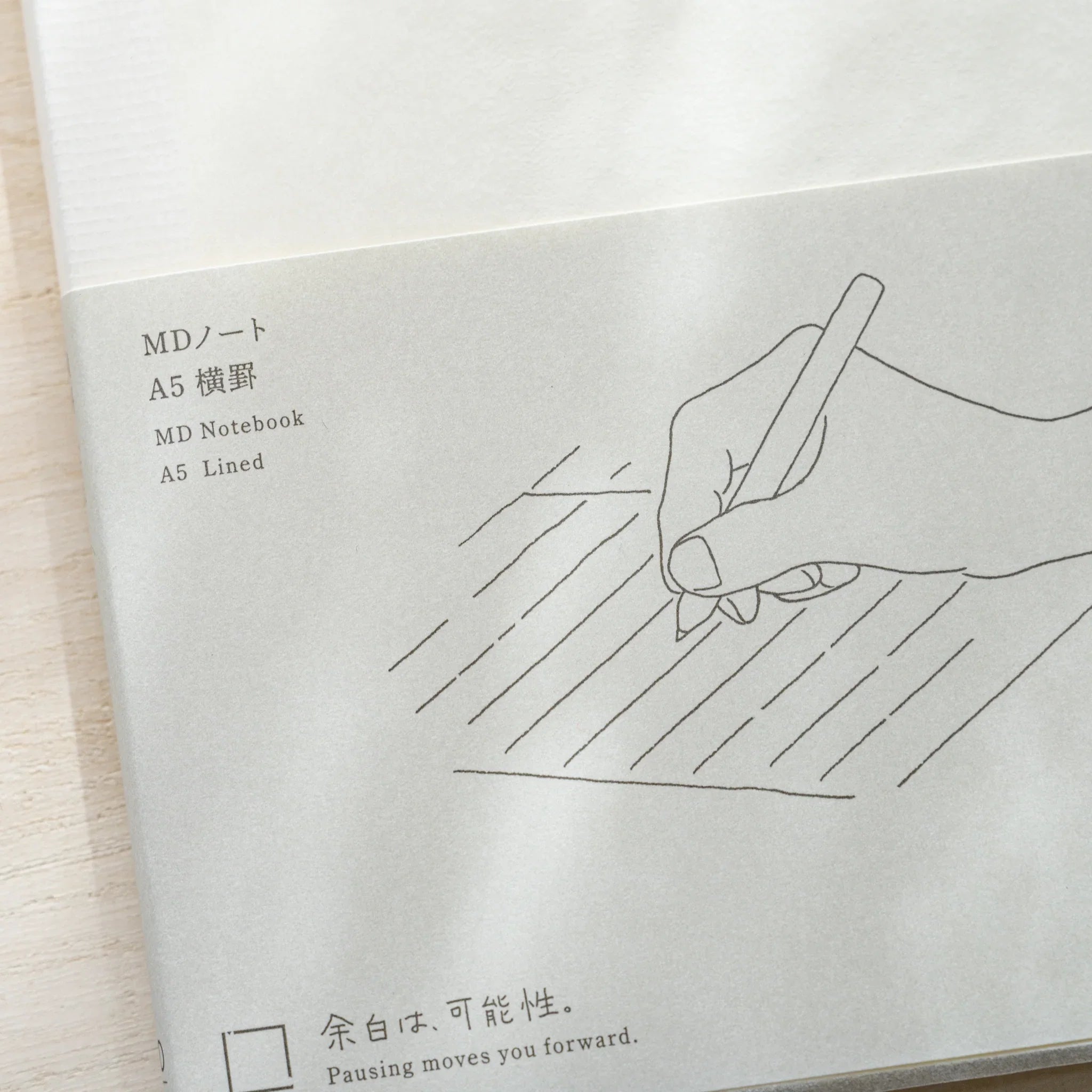 Close-up of Midori MD Notebook A5 Lined belly band showing hand writing illustration, MD Notebook A5 Lined text and tagline