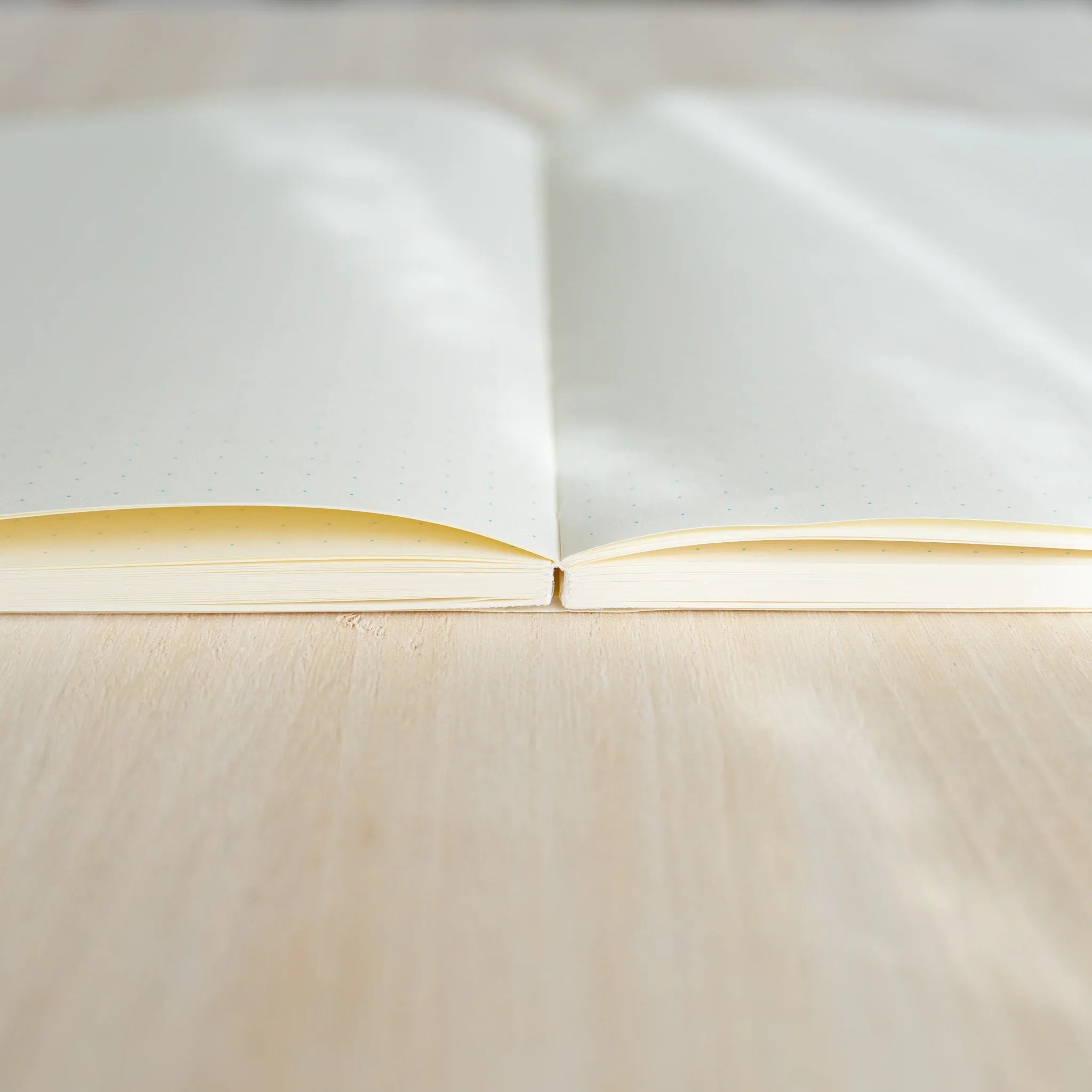 Midori MD Notebook A5 opened flat at 180 degrees, side view showing ivory paper pages and center thread-stitched binding