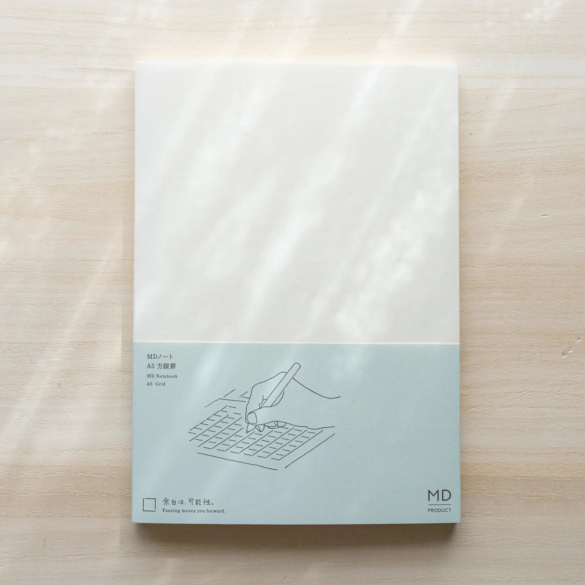 Midori MD Notebook A5 Grid belly band with teal line illustration of hand writing on grid, text MD Notebook A5 Grid