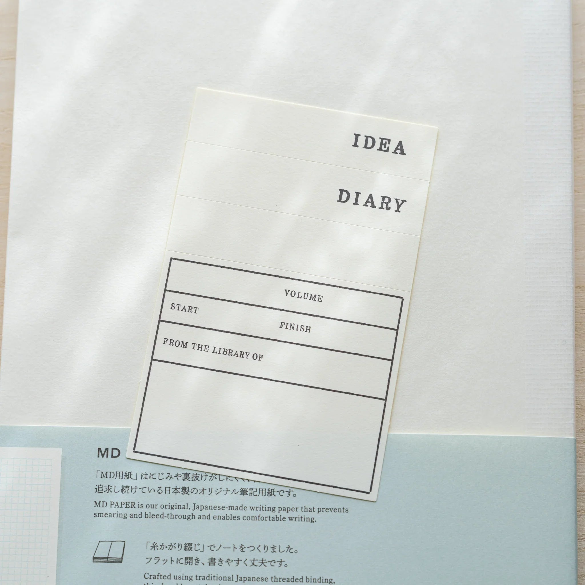 Midori MD Notebook A5 Grid in glassine wrapping, close-up of belly band IDEA Diary fill-in label with Volume, Start, Finish