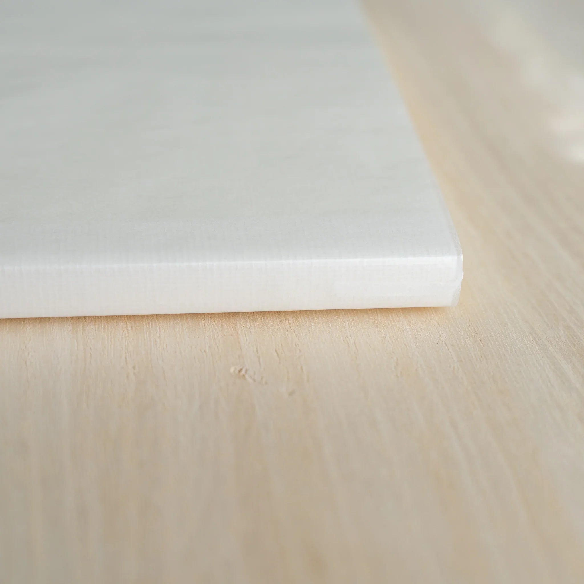 Close-up of Midori MD Notebook A5 spine corner showing ivory page stack, thread-stitched binding, and white satin ribbon