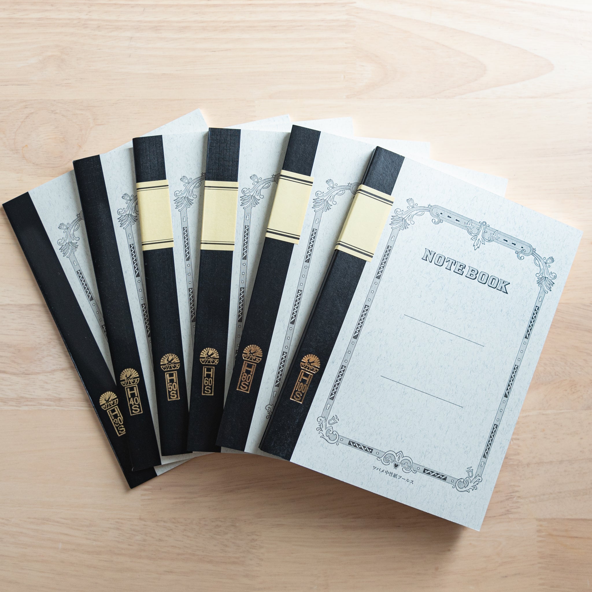 A set of Tsubame Japanese notebooks with decorative covers, black spine bindings, and gold lettering, showcasing high-quality Japanese stationery.  