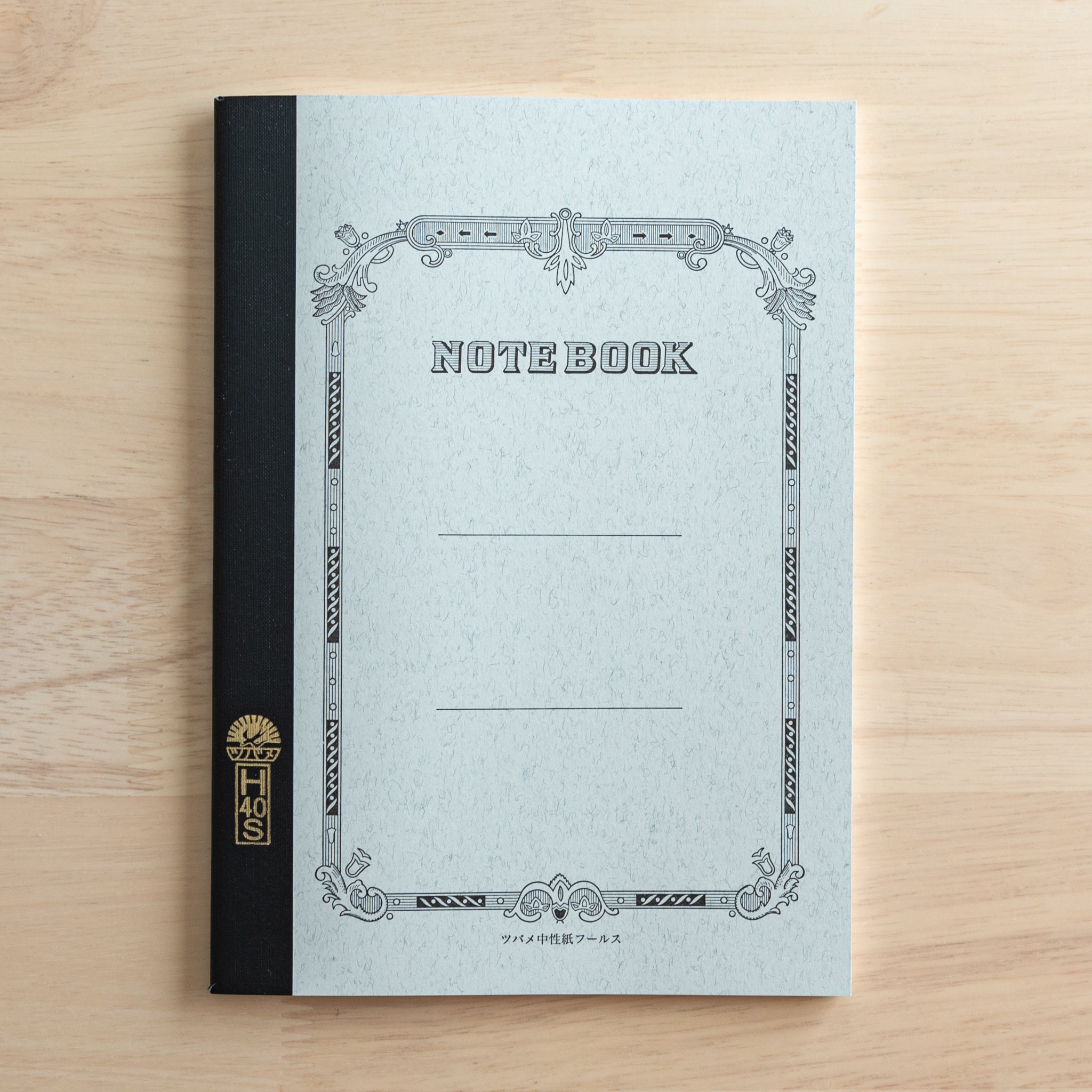 A Tsubame Japanese notebook with an ornate black and white cover design, featuring a black spine and gold lettering, representing high-quality Japanese stationery.  