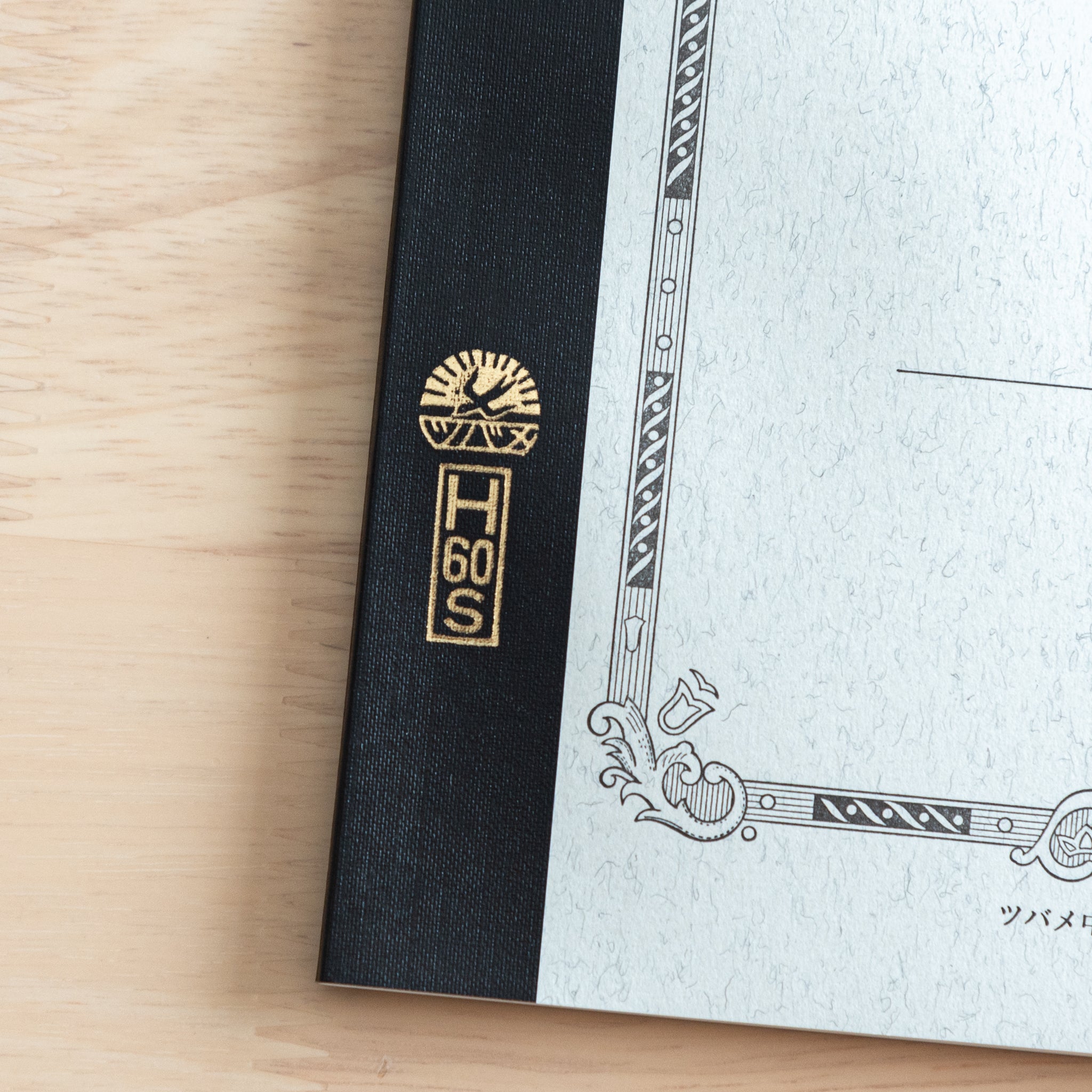 A close-up of the Tsubame Japanese notebook’s gold-stamped spine label, featuring the brand’s logo and model number, emphasizing fine Japanese stationery details.  