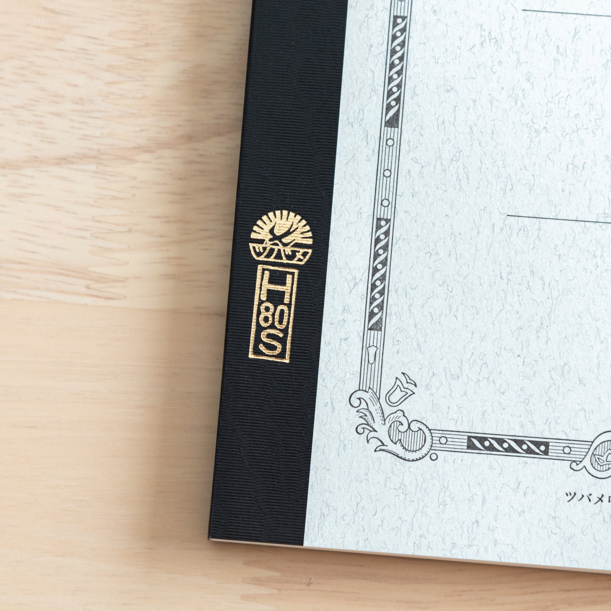 A close-up of the Tsubame Japanese notebook’s gold-stamped spine label, featuring the brand’s logo and model number, emphasizing fine Japanese stationery details.  