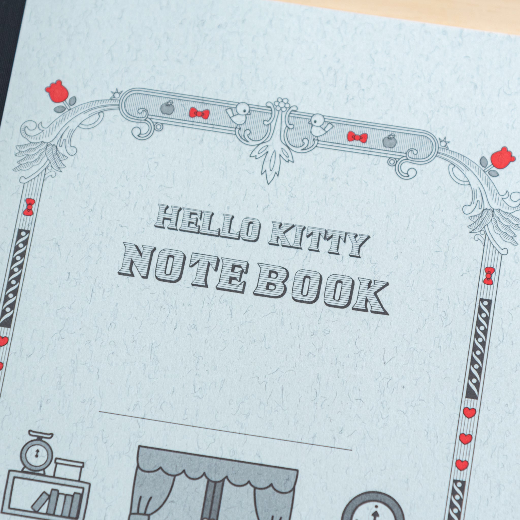 A close-up of the Tsubame Japanese notebook’s cover, showcasing "HELLO KITTY NOTEBOOK" in bold letters with intricate black and red decorative elements.  