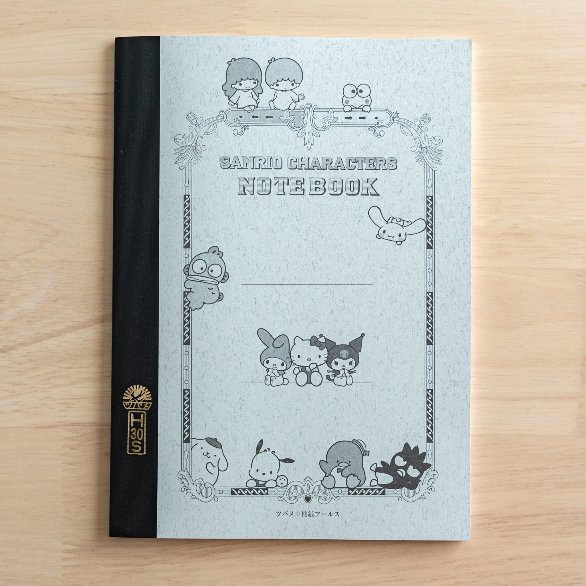 A Japanese notebook with a black spine and a gray cover featuring Sanrio characters in a vintage-style frame. "SANRIO CHARACTERS NOTEBOOK" is printed in the center.  