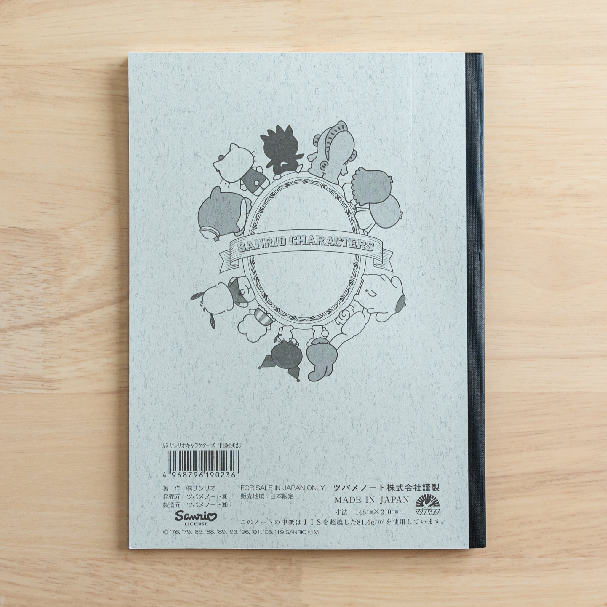 The back cover of a Tsubame Japanese notebook with a Hello Kitty design, featuring a piano illustration, a black spine, product details, and a "Made in Japan" label.  