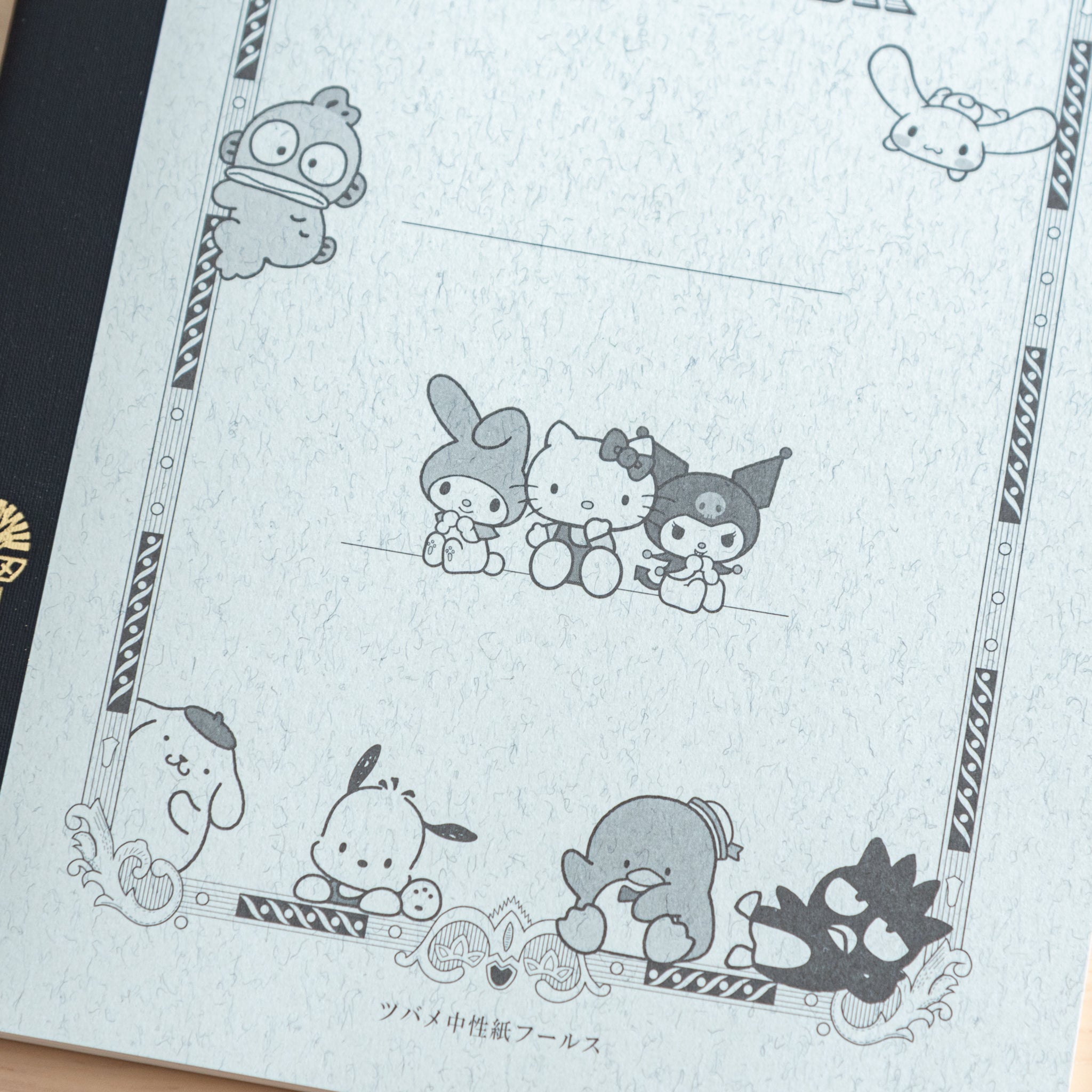 A detailed view of a Japanese notebook cover showcasing Sanrio characters like Pompompurin and Badtz-Maru in a classic design with ornate borders.  