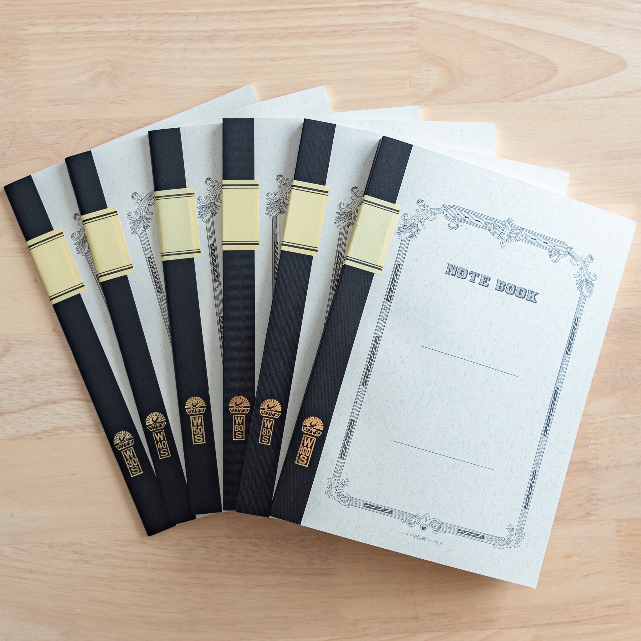 A set of Tsubame Japanese notebooks with decorative covers, black spine bindings, and gold lettering, showcasing high-quality Japanese stationery.  