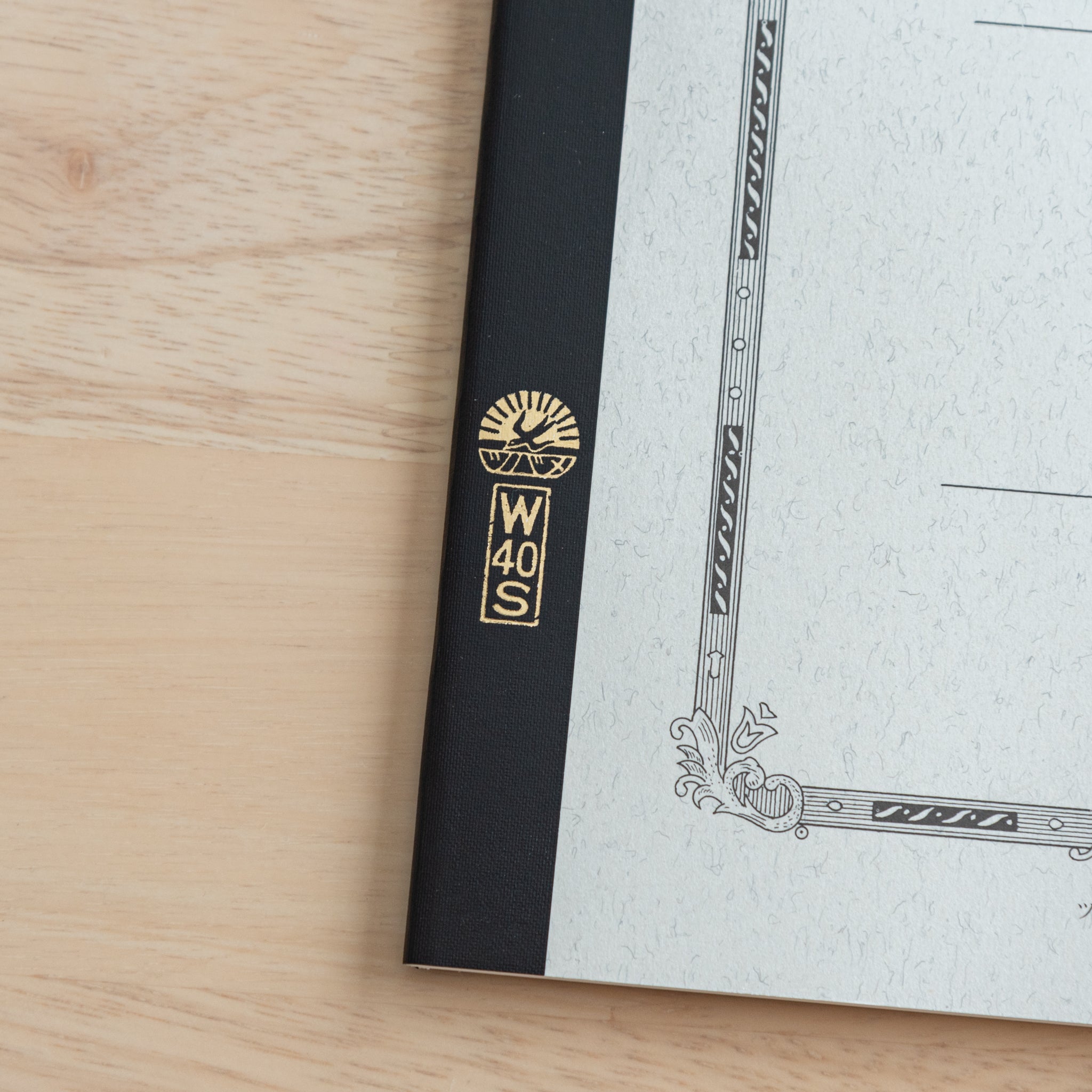 A close-up of the Tsubame Japanese notebook’s gold-stamped spine label, featuring the brand’s logo and model number, emphasizing fine Japanese stationery details.  