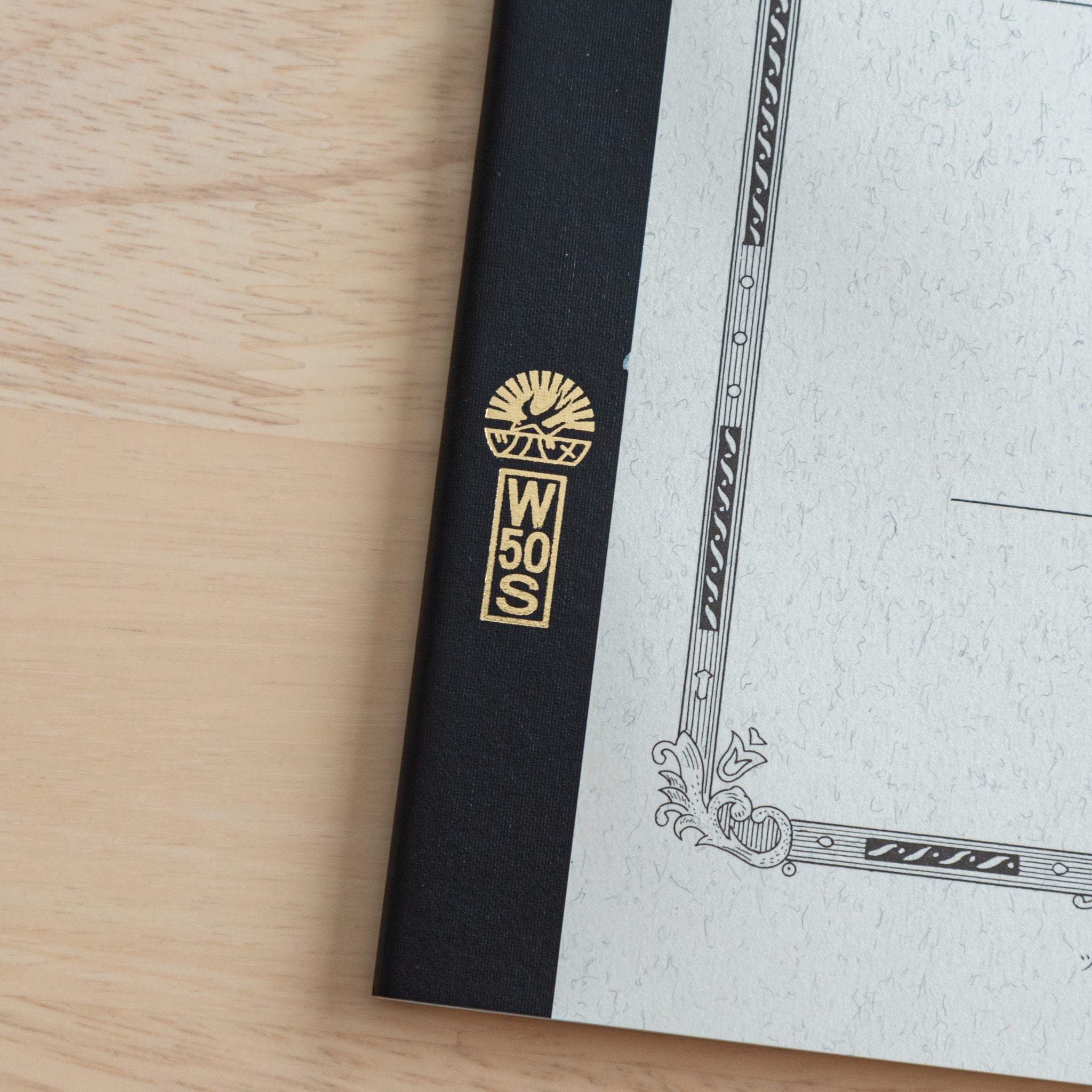 A close-up of the Tsubame Japanese notebook’s gold-stamped spine label, featuring the brand’s logo and model number, emphasizing fine Japanese stationery details.  